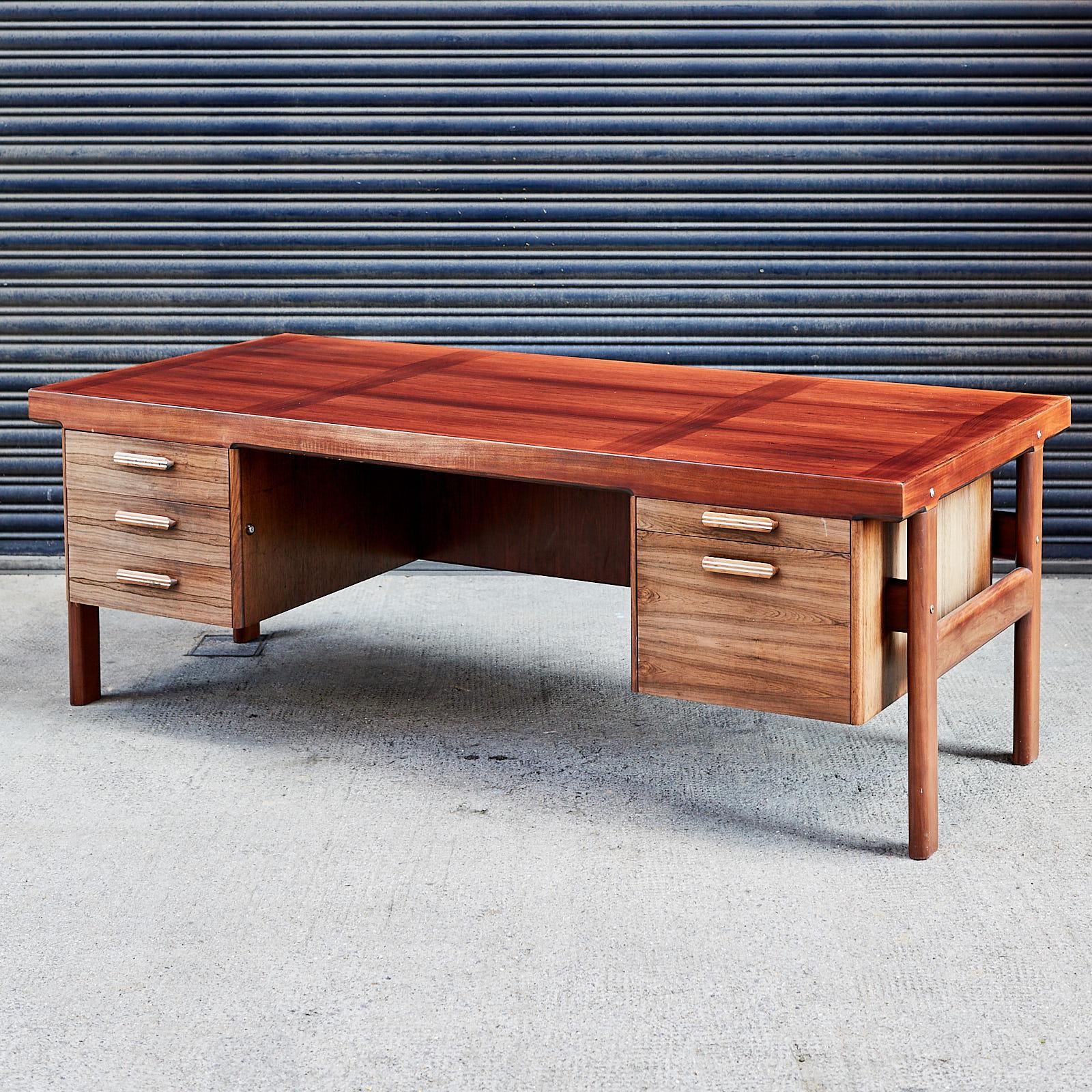 A large midcentury rosewood writing desk, 'Presidents Desk', designed by Arne Vodder for Danish manufacturer Sibast in 1960. Minor loss to one corner of desk, with characterful sun bleaching throughout.