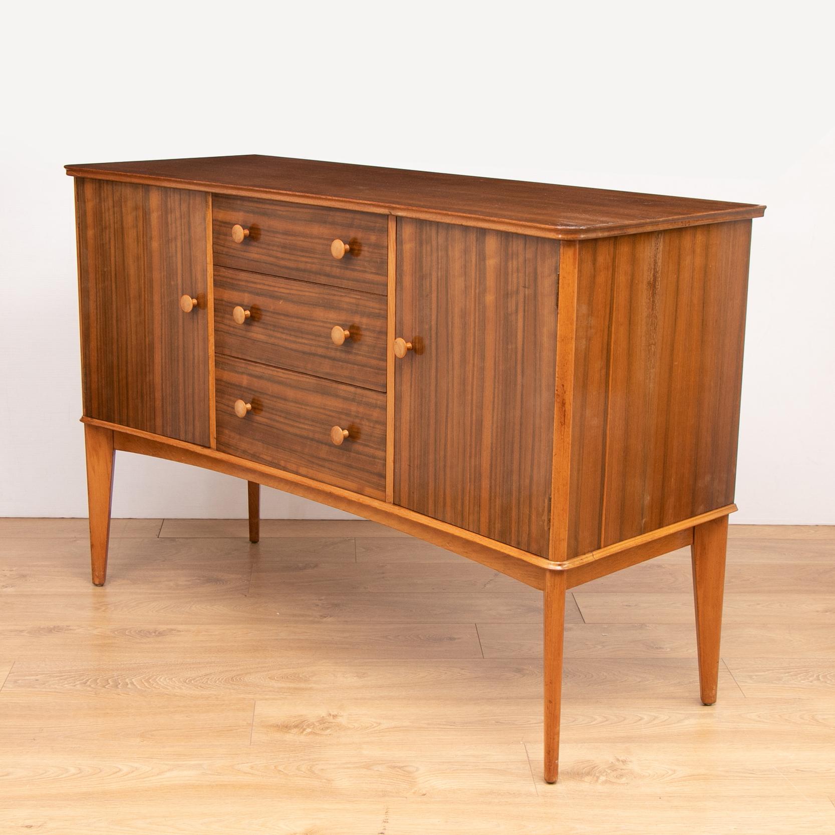 A midcentury rosewood sideboard by Gordon Russell Ltd, England, 1955. The sideboard contains three drawers and three storage compartments. The sideboard was bought as wedding present in 1955 from Bourne & Hollingsworth department store on Oxford