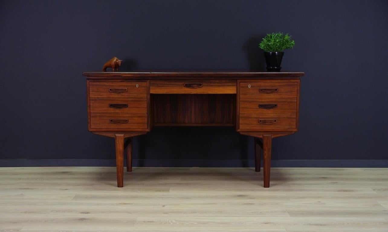 Unpretentious desk of the 1960s-1970s. Beautiful straight line - Scandinavian design with rosewood veneer. Seven practical drawers and at the back bookshelves with bar. Rosewood wood handles and legs. Key included. Desk in good condition (minor