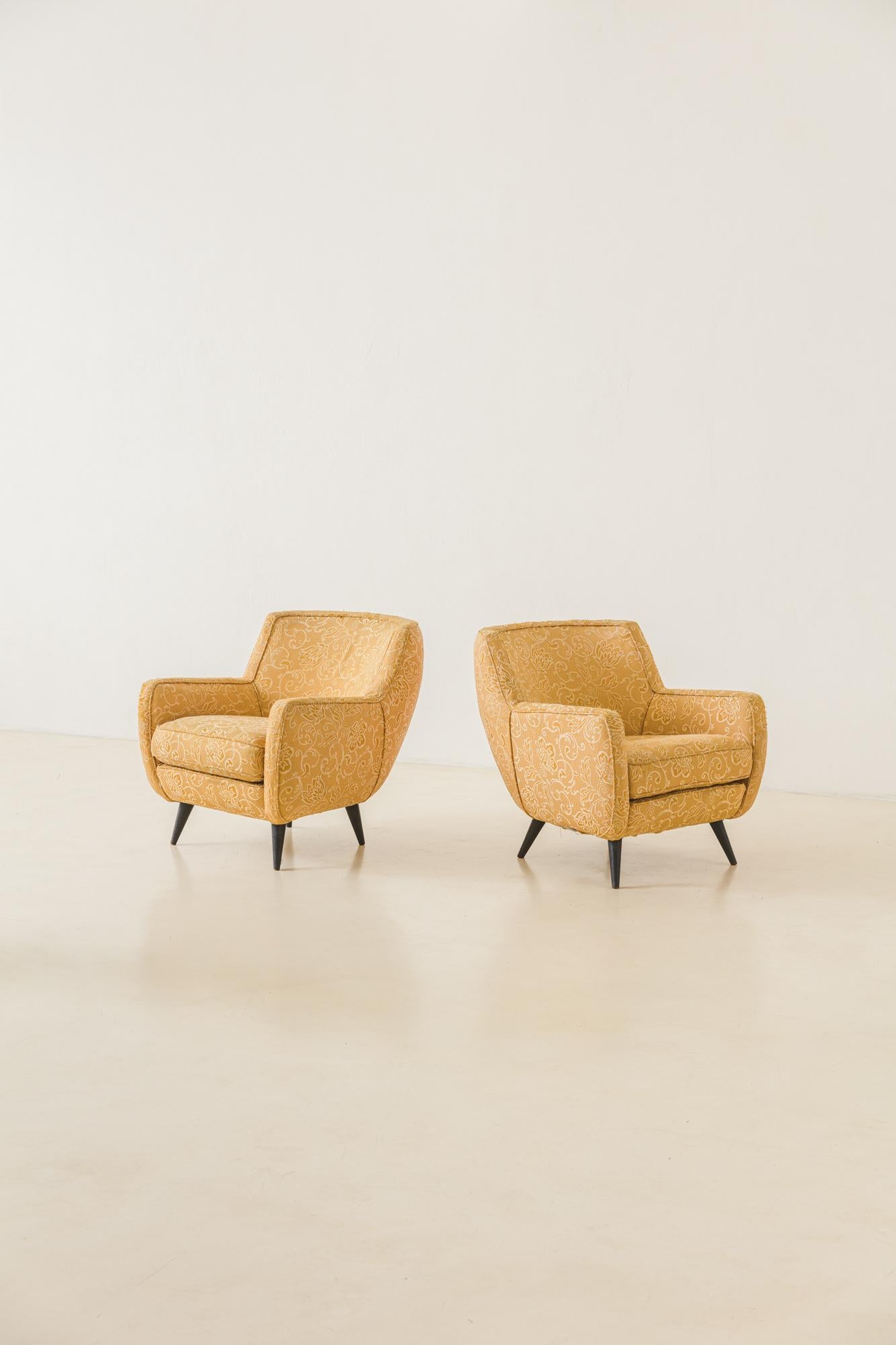Cette incroyable paire de fauteuils arrondis, conçue par Geraldo de Barros (1923-1998) et fabriquée par Unilabor, présente une structure en bois avec un revêtement en tissu et des pieds tournés pointus en bois massif. Les pièces sont en état