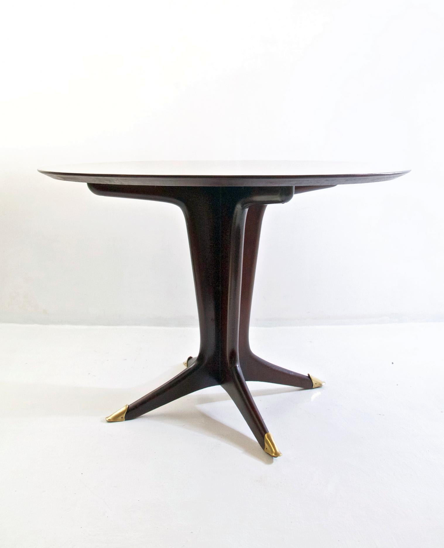 A stunningly beautiful midcentury round dining table in walnut and brass capped feet. The tabletop which has been bookmatched rests on a center pillar in wood with four legs. The entire table has been restored and is in perfect condition.