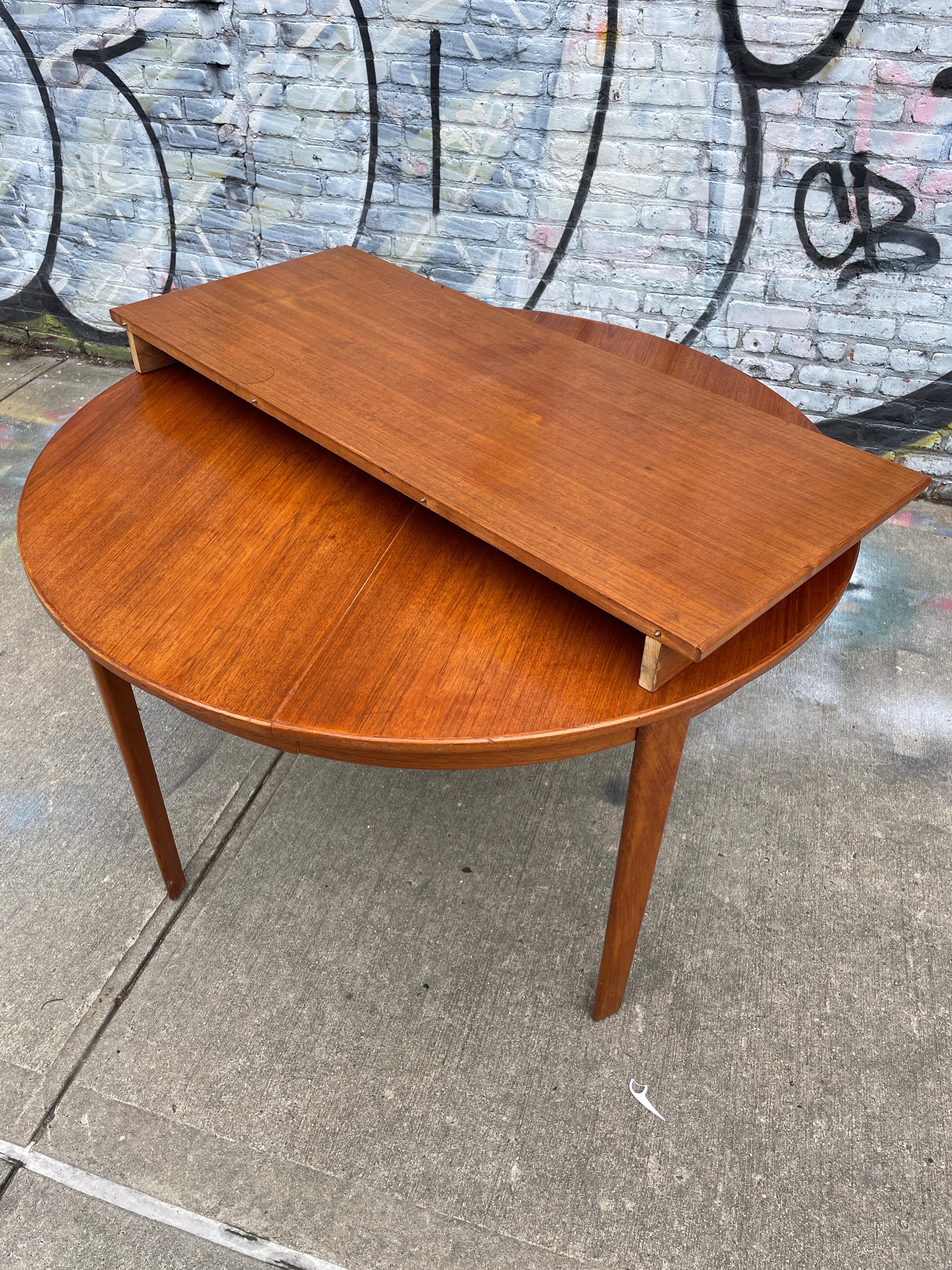Midcentury teak round Danish Modern extension dining table with (3) leaves. This table has Solid teak legs that unscrew with bolts. This table is in good vintage condition shows signs of use, (1) leaf with matches the table 100% and has an apron.