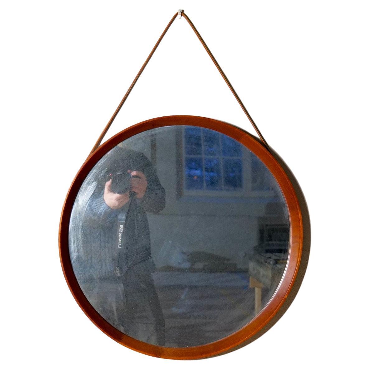 Wonderful organic rounded wall mirror produced by AB Glas & Trä, Hovmantorp, Sweden. This rounded and crafted crystal mirror glass was med with a teak frame and leather. 

Good vintage condition, with some scratches on the wood. Distressed