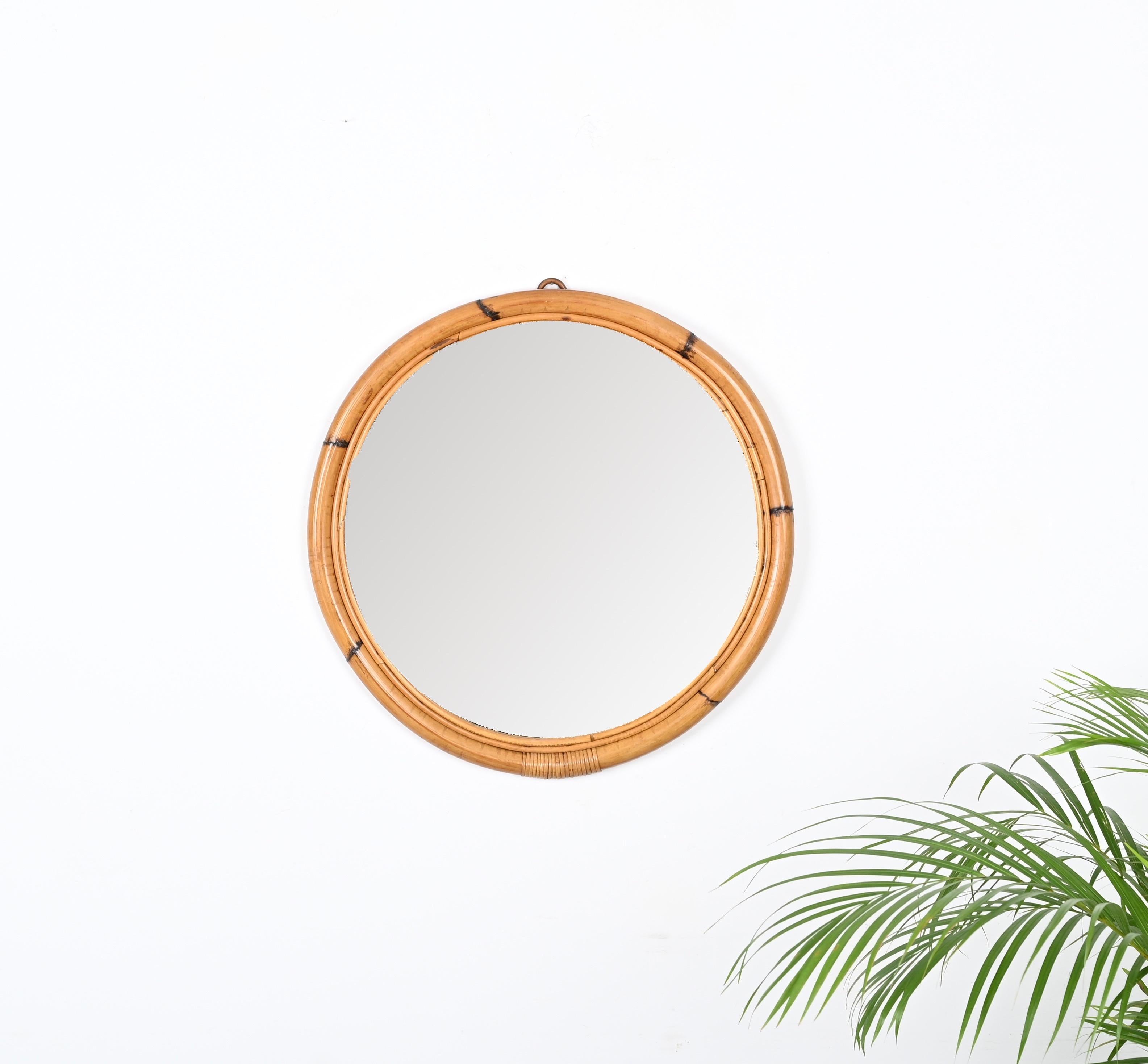Wonderful mid-century round mirror with double bamboo cane frame. This fantastic item was produced in Italy in the 1970s.

The mirror features a double round frame, the external one in curved bamboo and the inside one in curved rattan. The mirror is