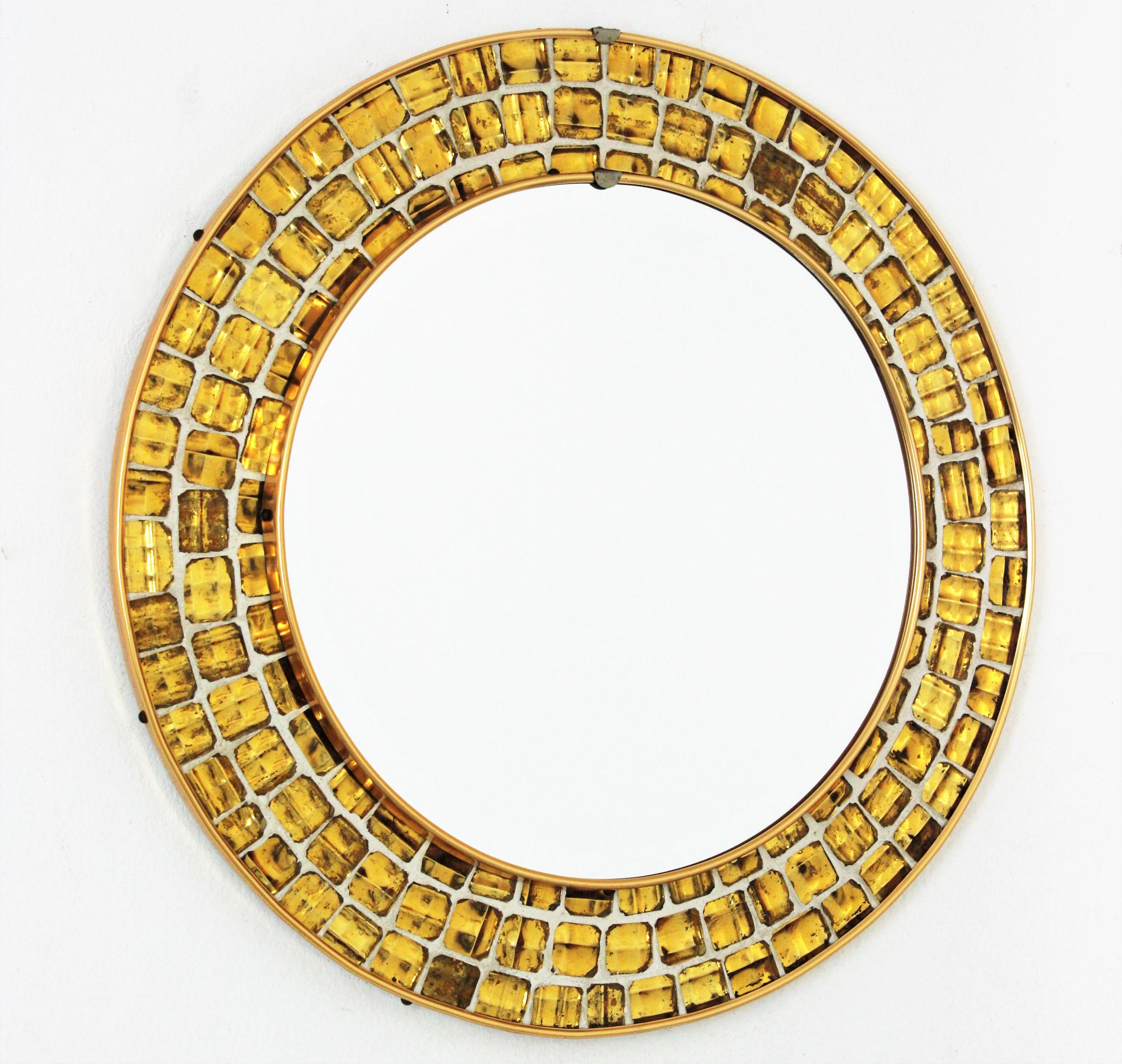 Spanish midcentury mosaic round mirror framed with golden textured glass tiles. Spain, 1960s.
This gorgeous Mid-Century Modern mirror features a tile mosaic with small pieces of textured irisdiscent glass in gold color cased on a white background