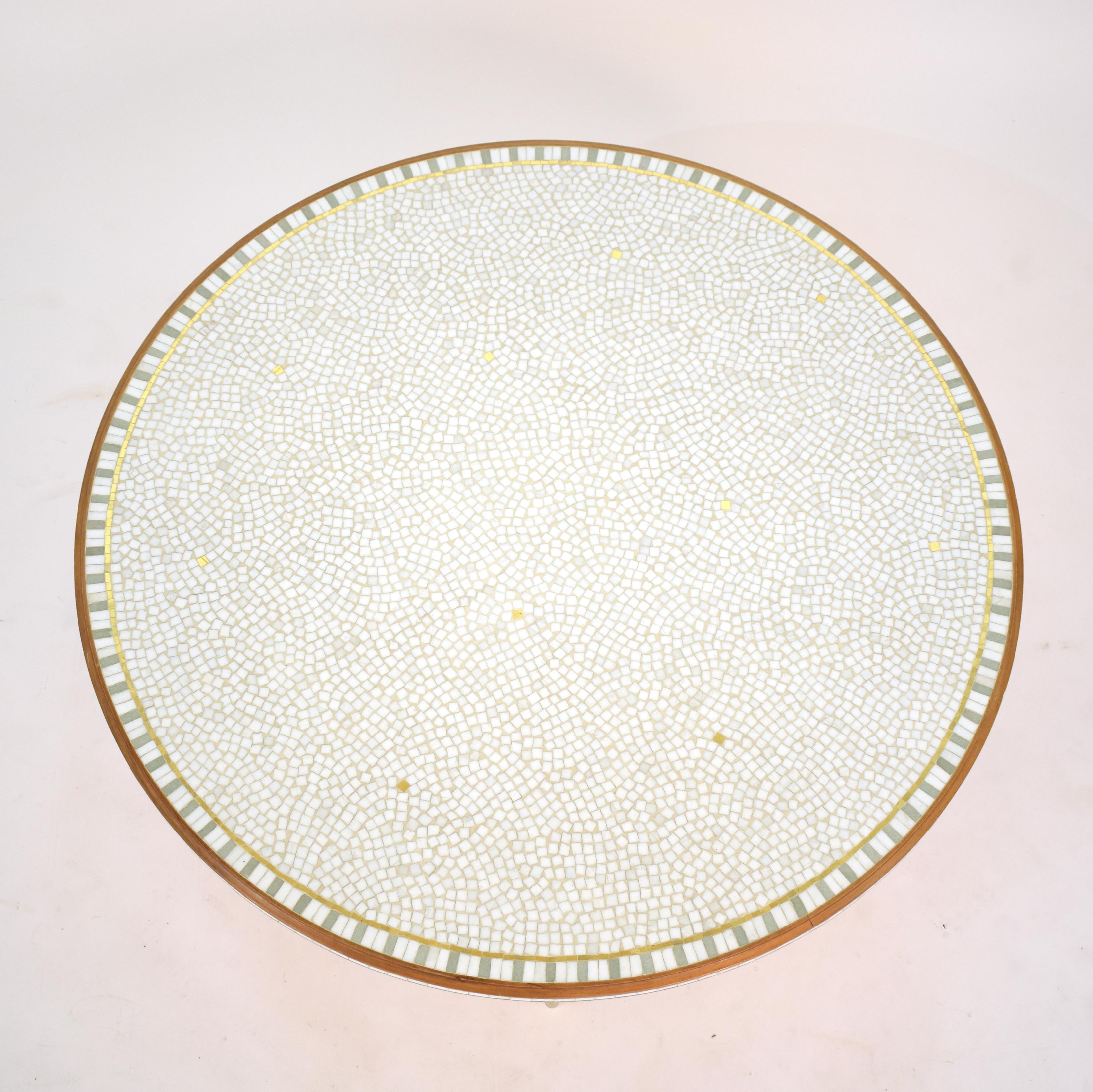 This beautiful and elegant round mosaic top coffee table with a walnut frame and legs was designed by the German artist and sculptor Berthold Muller, (1893-1979).
The top has white ceramic stones combined with gold and some mint green ceramic