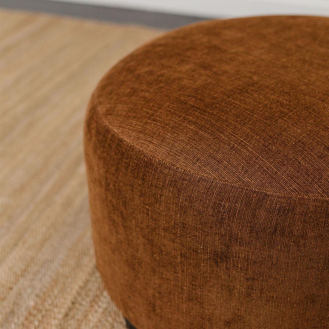 A round ottoman reupholstered in a Designs of the Time linen + jute blend. Its simple yet sophisticated silhouette makes it a versatile choice for various interior styles and is suitable for both small and spacious room.