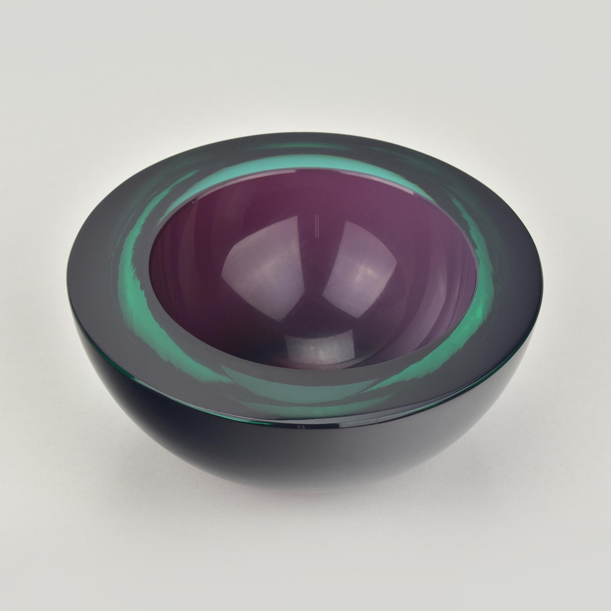 Coupe ronde en verre, réalisée selon la technique du Sommerso à partir de verre améthyste et vert foncé, conçue par Flavio Poli pour Seguso Vetri d'Arte. Grâce à sa polyvalence, ce bol peut être utilisé comme cendrier, vide-poche ou porte-bijoux, ce