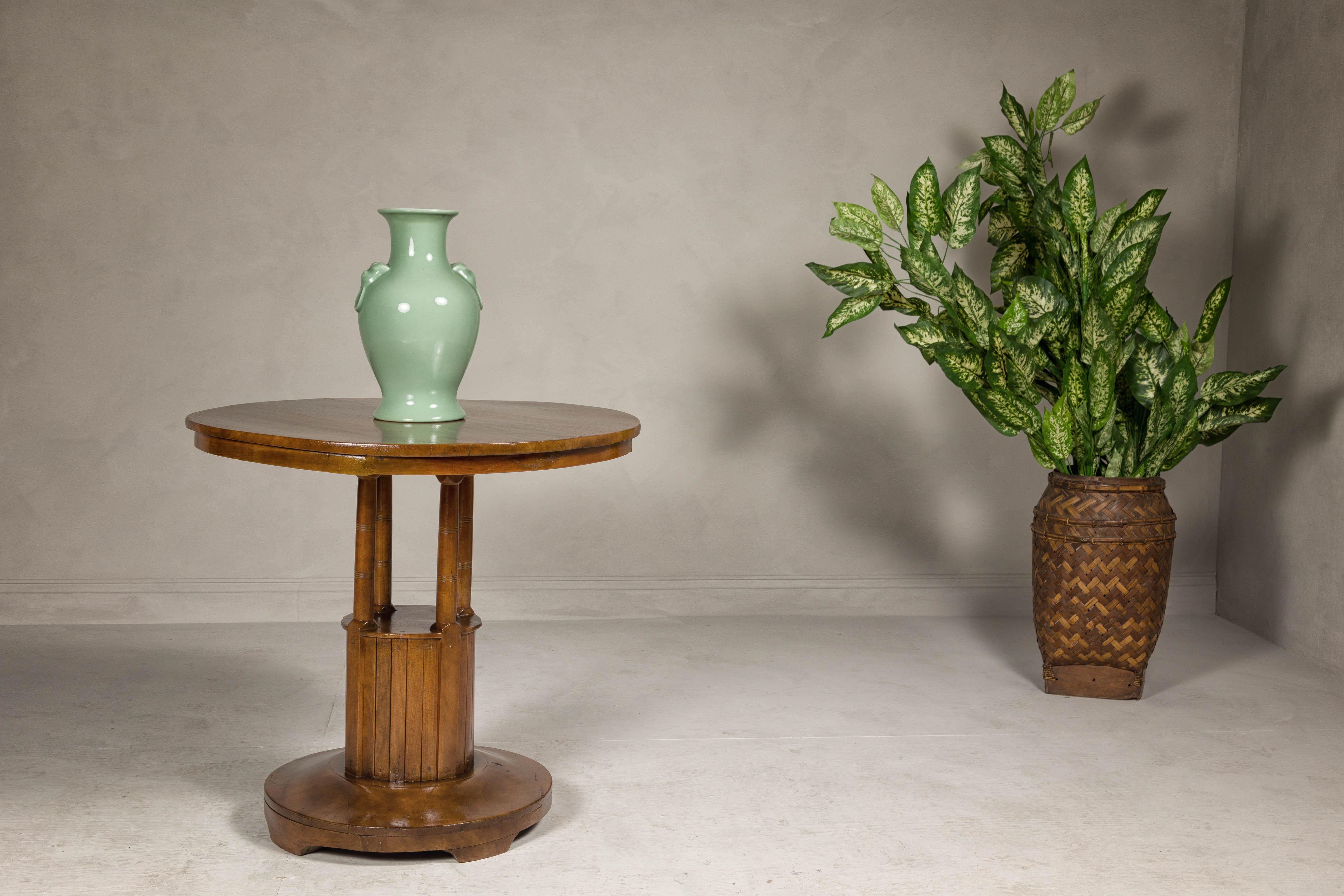 A Midcentury wooden side table with round top, column-shaped supports and tambour base. This Midcentury wooden side table exudes timeless charm and elegance, featuring a round top supported by slender, column-shaped supports adorned with reeded