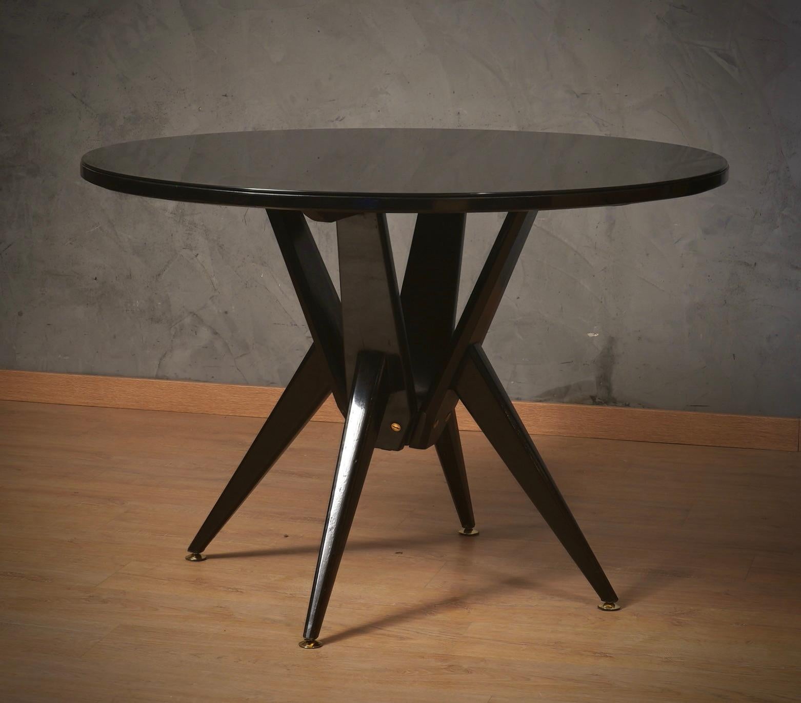 Table très spéciale en bois ébonisé et verre noir ; elle présente une élégance architecturale qui rappelle les projets structurels renommés de Pietro Chiesa, Ico Parisi, Vittorio Dassi, attribués à un fabricant italien de la première moitié du