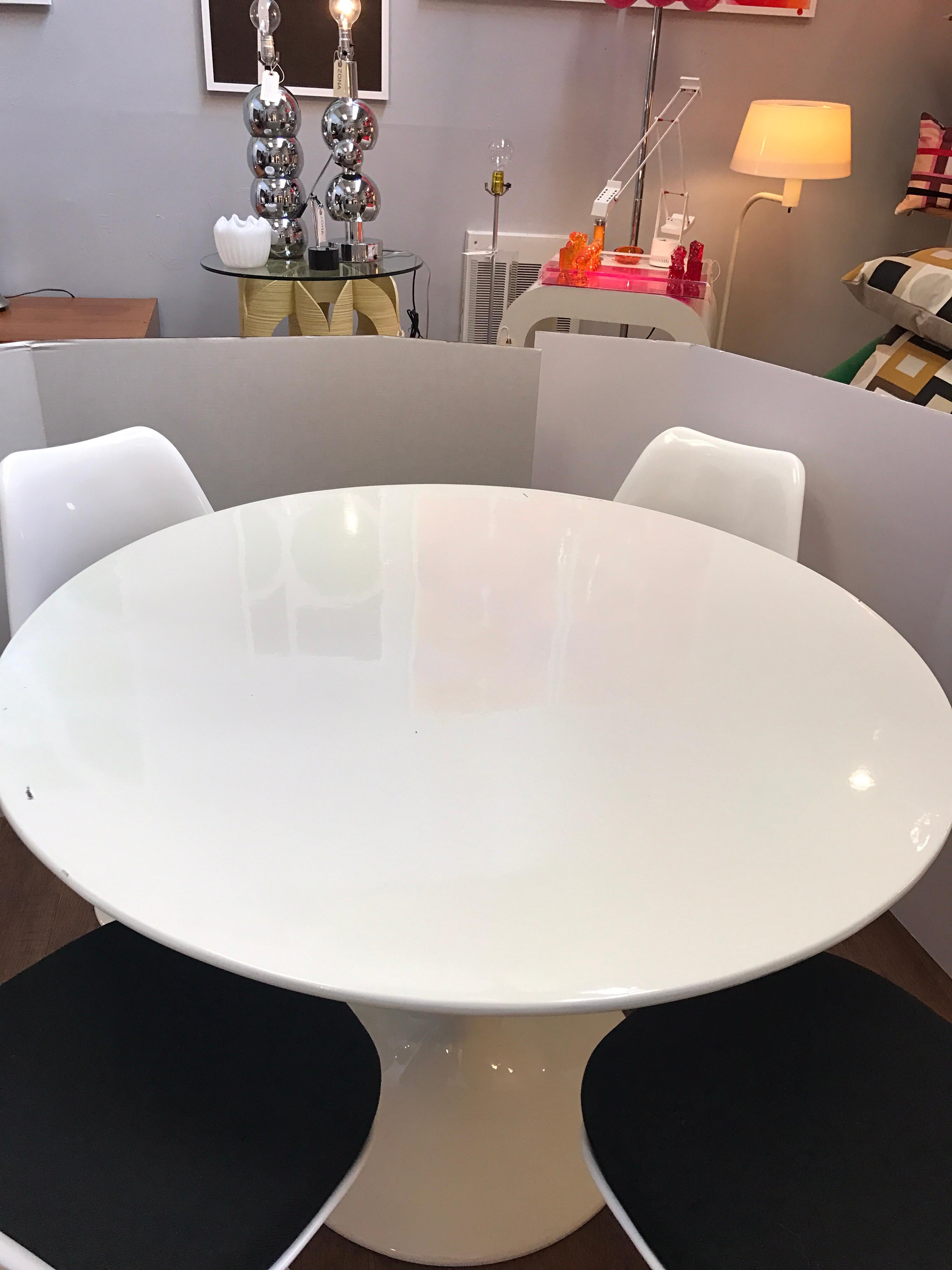 Mid-Century Modern Saarinen style tulip table and four chairs with black wool seats. Table dimensions are below and dimensions of chairs are 31 inches high by 18.5 inches wide by 19.5 inches deep.