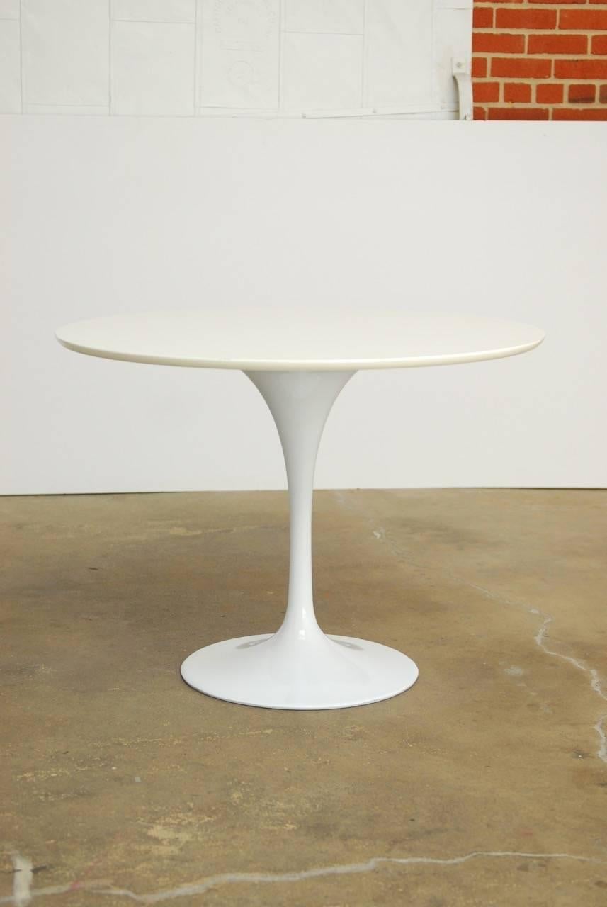 Breakfast table size midcentury white tulip table in the manner of Eero Saarinen. Features a metal base with a round white laminate top.

