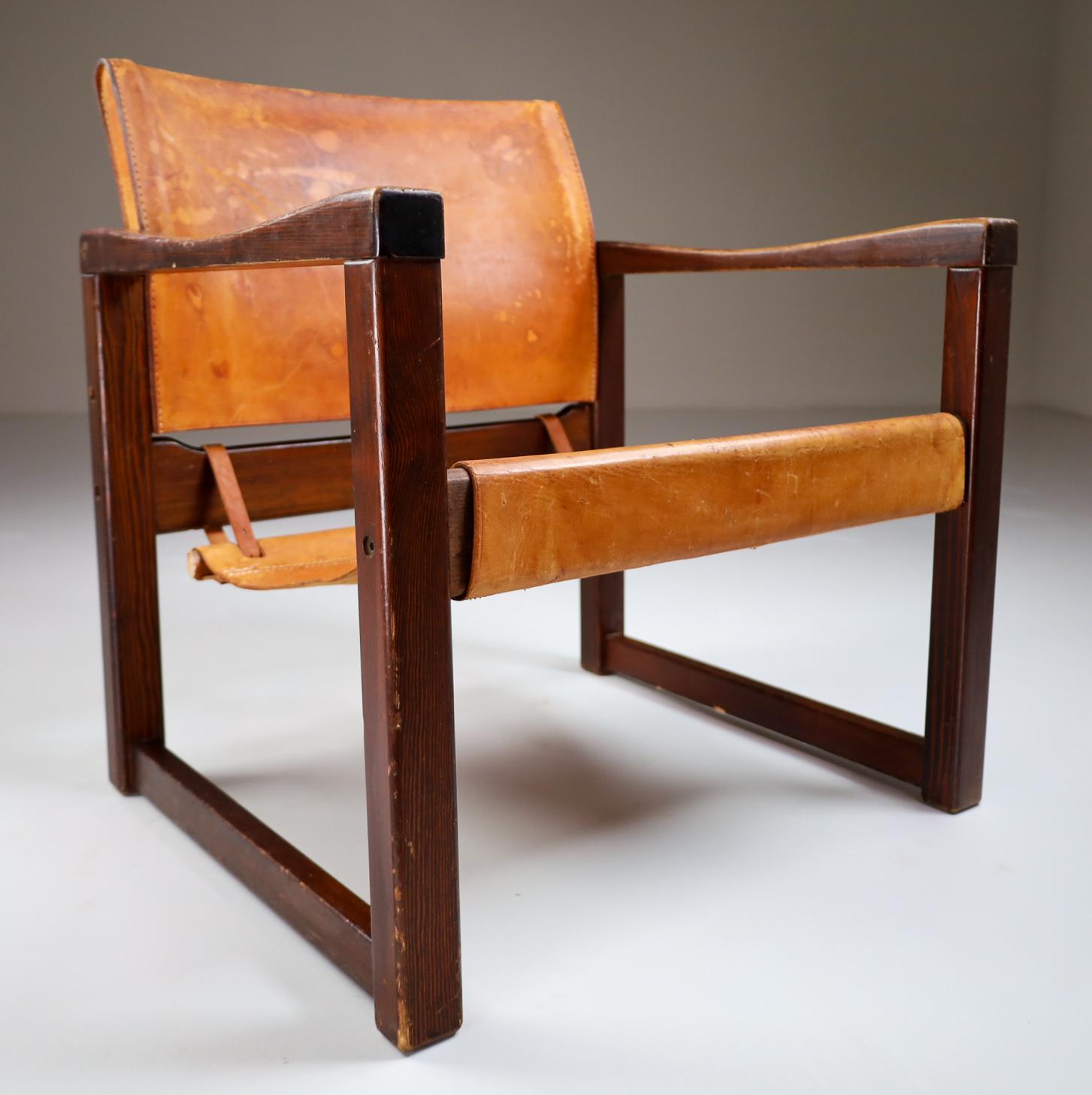 Safari lounge chair in absolutely gorgeous patinated cognac saddle leather and solid pinewood, circa 1970s. The thick saddle leather is beautifully patinated during use and age and shows interesting stitching. European pine wood with thick saddle