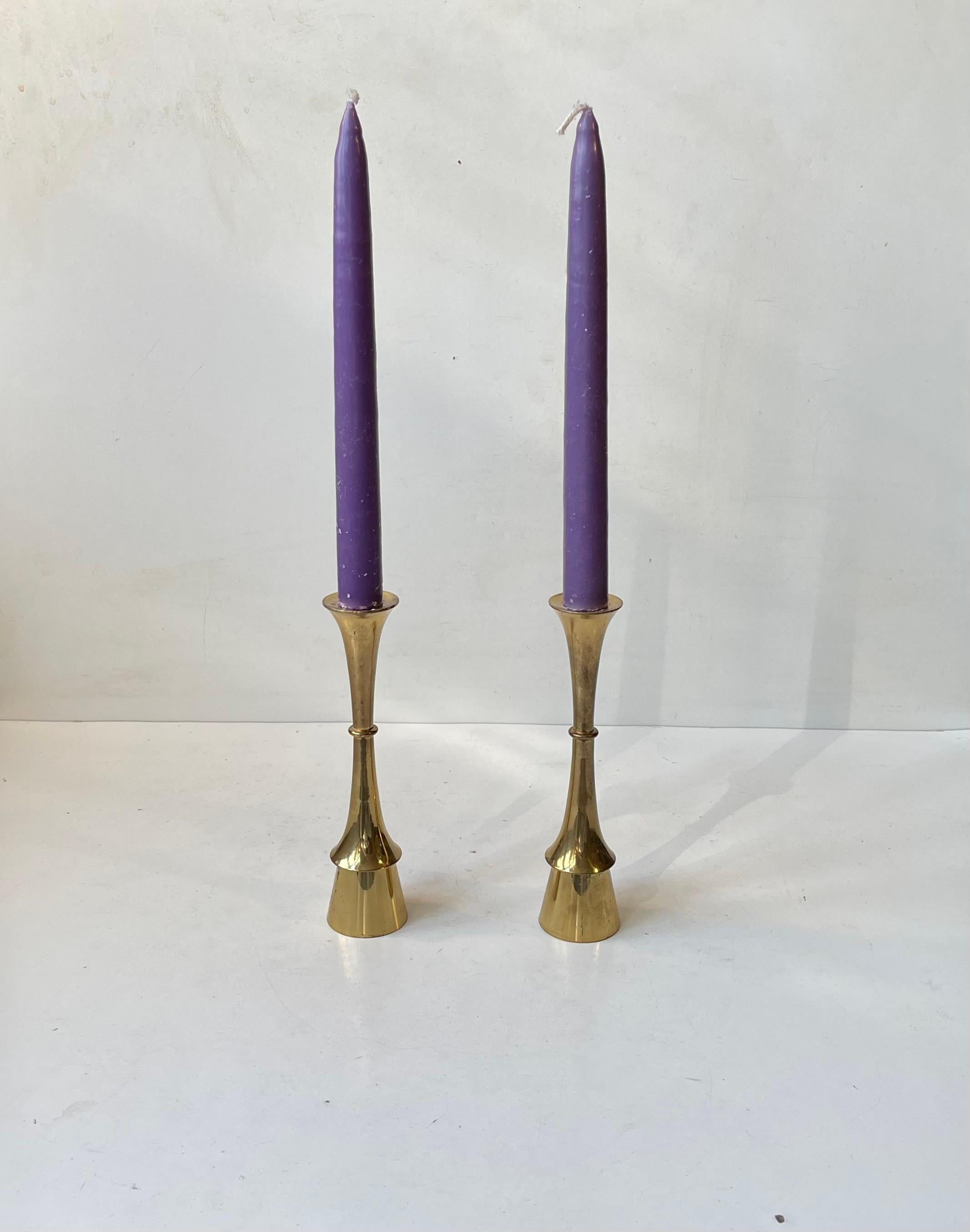 A pair of solid brass candlesticks designed and manufactured by Hyslop in Copenhagen, Denmark during the 1960s. The candlesticks are to be fitted with regular sized candles. They have not been polished recently and display patina. The style of this