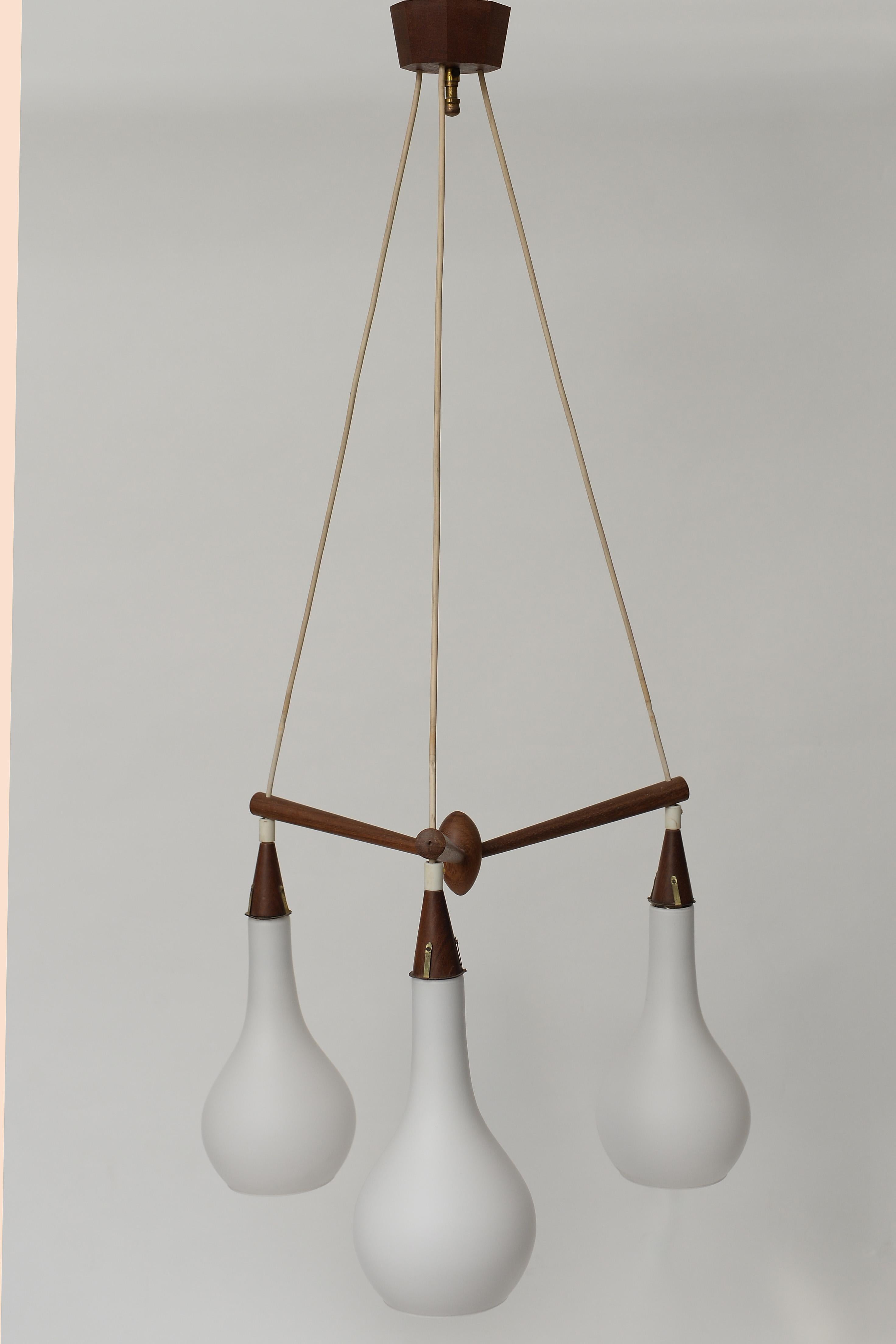 Midcentury Scandinavian chandelier made of teak with teardrop shaped milk glass shades.

The teak chandelier is in perfect condition and has the original teak ceiling canopy.

It creates a warm and charming atmosphere.

Tested and ready for