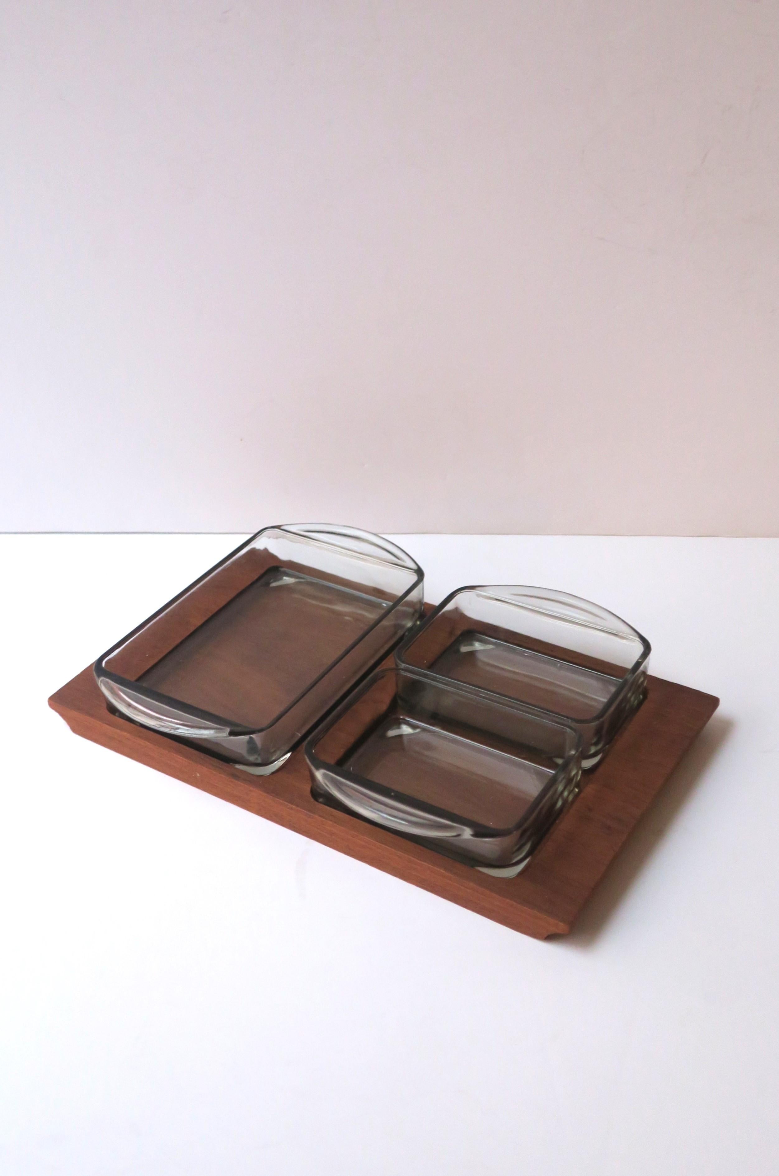 A wood and glass serving dish with three compartments, Midcentury Danish Modern or Scandinavia Modern design period, circa mid-20th century, Denmark. Piece has a wood base with three glass dishes in a light smoked blue hue, each glass dish has a lip