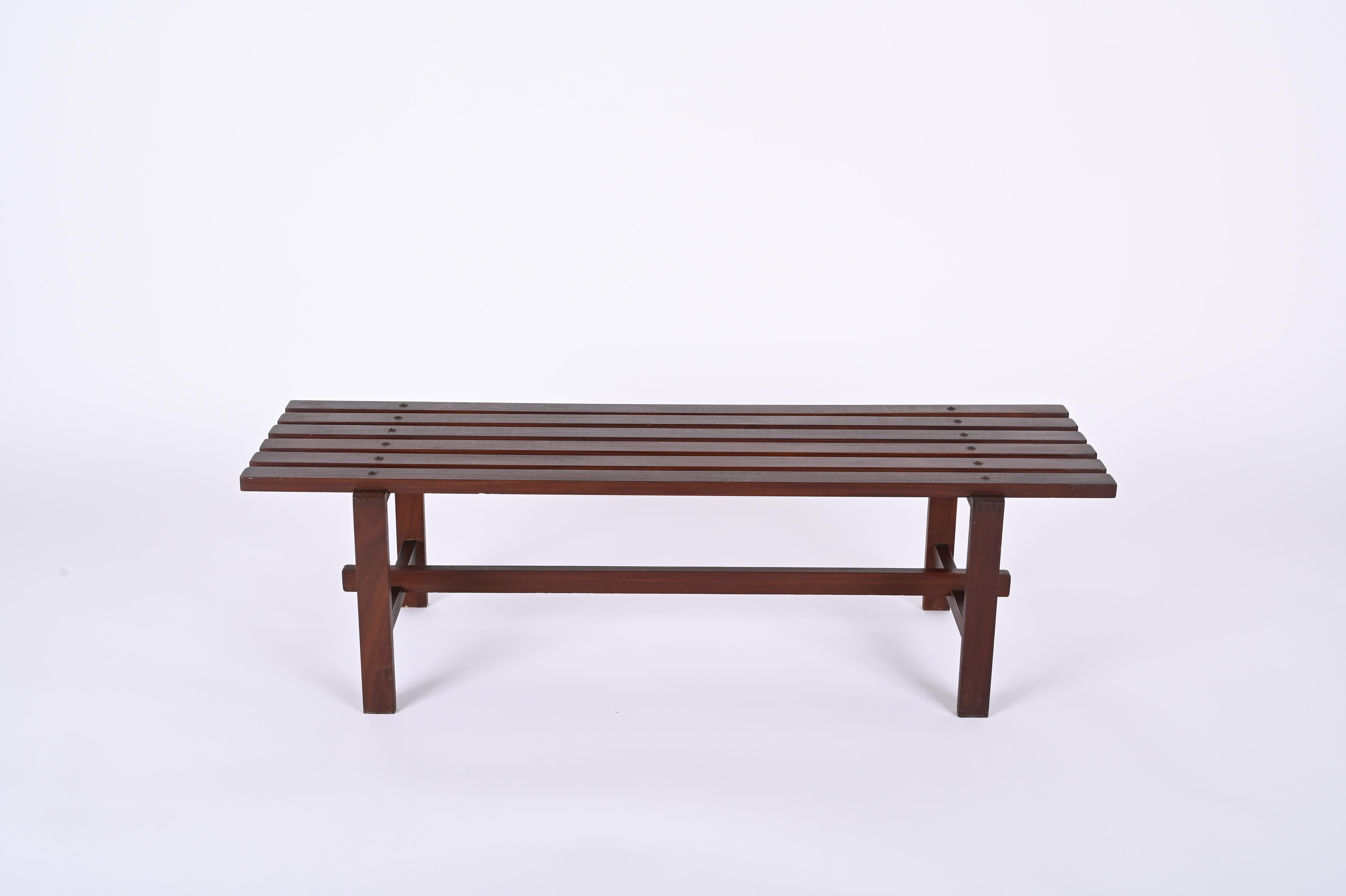 Meravigliosa panca di metà secolo realizzata in legno di teak marrone scuro. Questo stupefacente articolo è una produzione scandinava degli anni '60. 

Il pezzo è composto da sei pezzi di legno orizzontali per la seduta e da una struttura fatta di