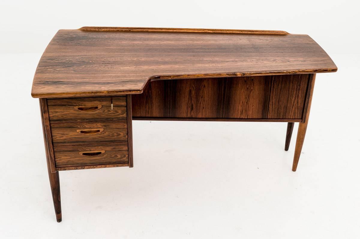 A desk in rosewood by Göran Strand for Lelångs Möbelfabrik, Sweden, 1950s. This asymmetric-shaped desk shows beautiful details and great design quality. In the front you find three drawers with beautifully shaped handles and a lock on the upper