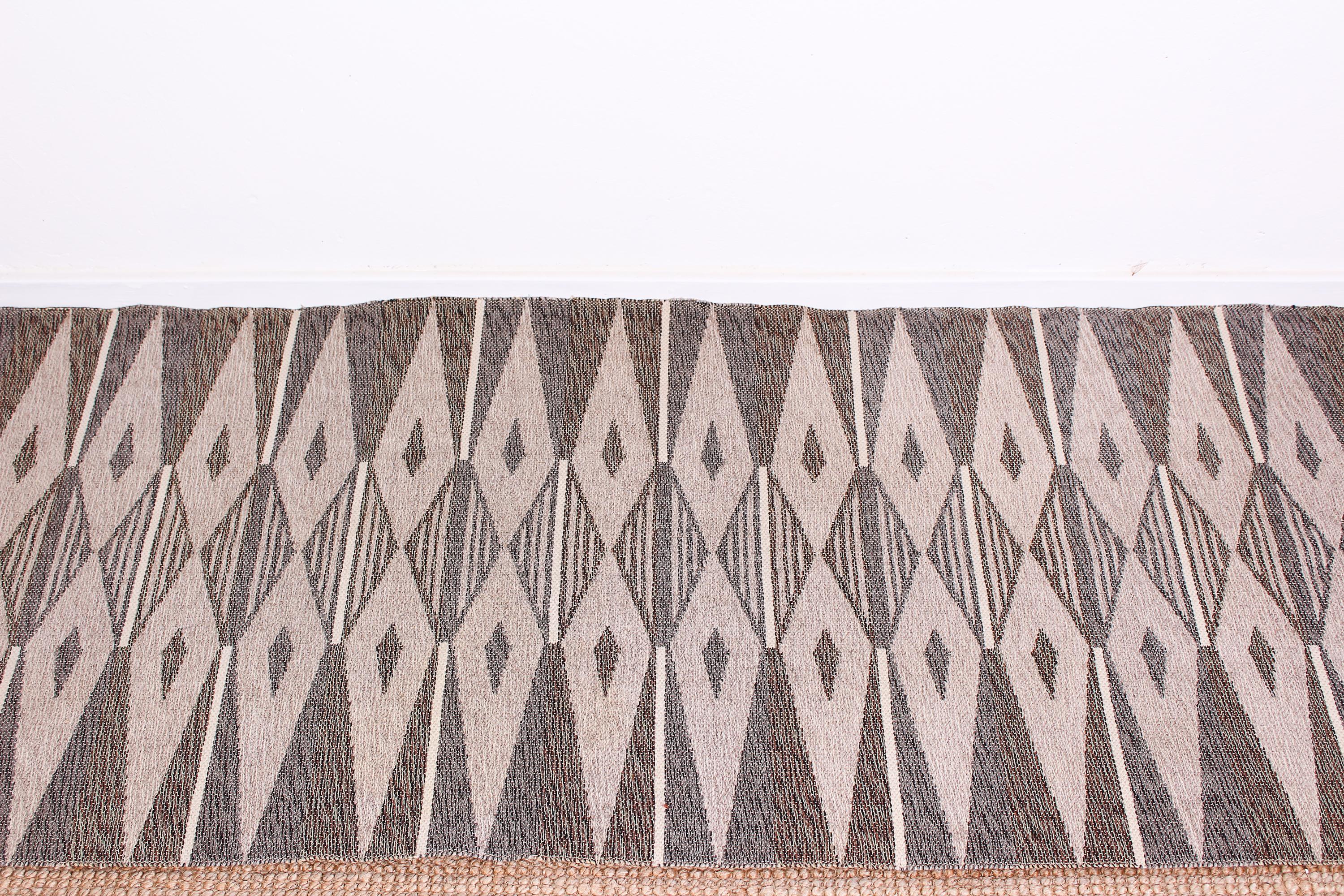 This midcentury Scandinavian (most likely Finland) carpet is made with dubble weave technique and can therefor be used with either side up. The carpet has a beautiful geometrical pattern and grey scale of colors. Very good vintage condition with