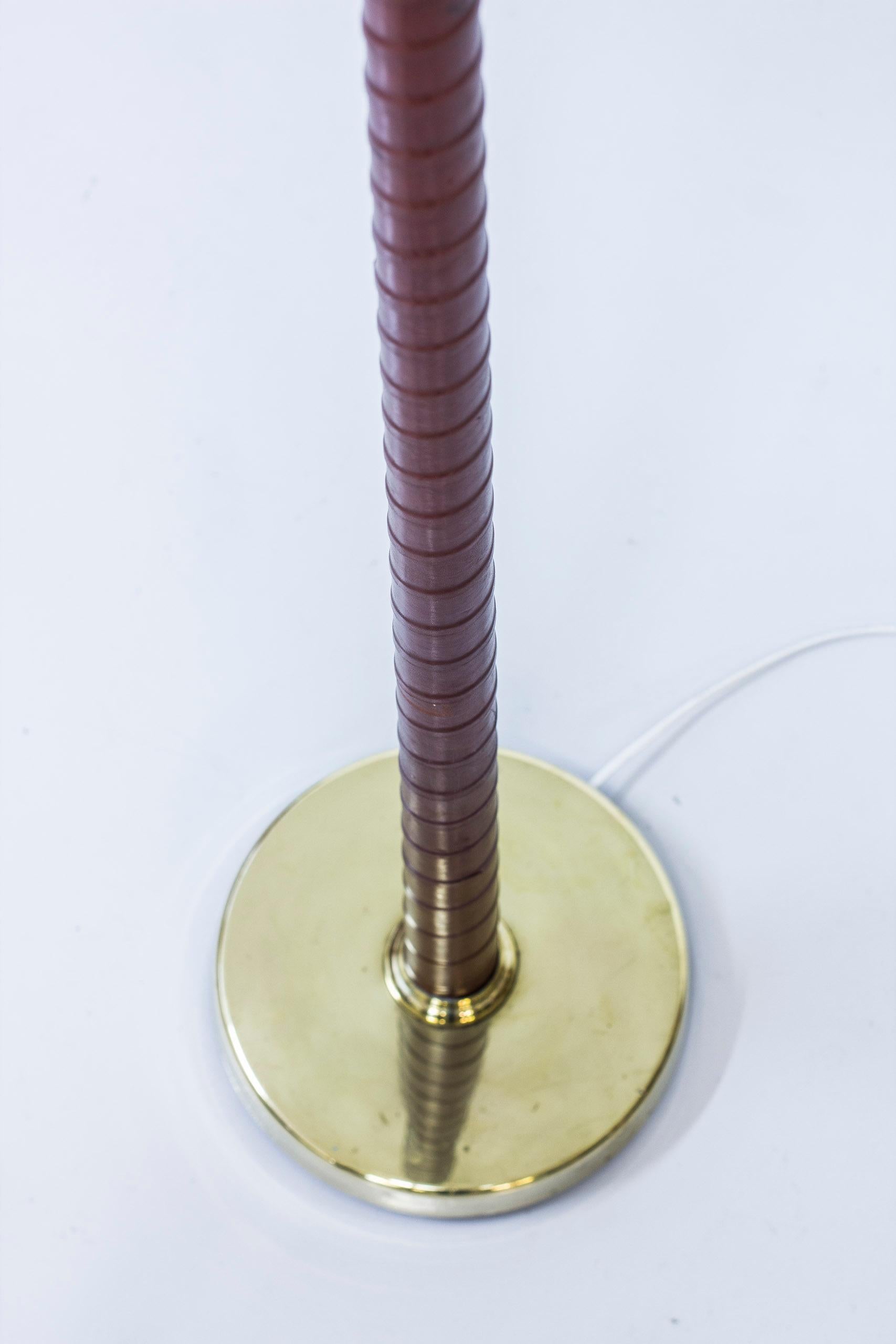 Rare floor lamp designed by Hans Bergström. Produced by his own company Ateljé Lyktan during the 1940s. Made from solid brass with hand wrapped leather in burgundy. Glass diffuser with original lamp shade with new white linen fabric. The lamp has