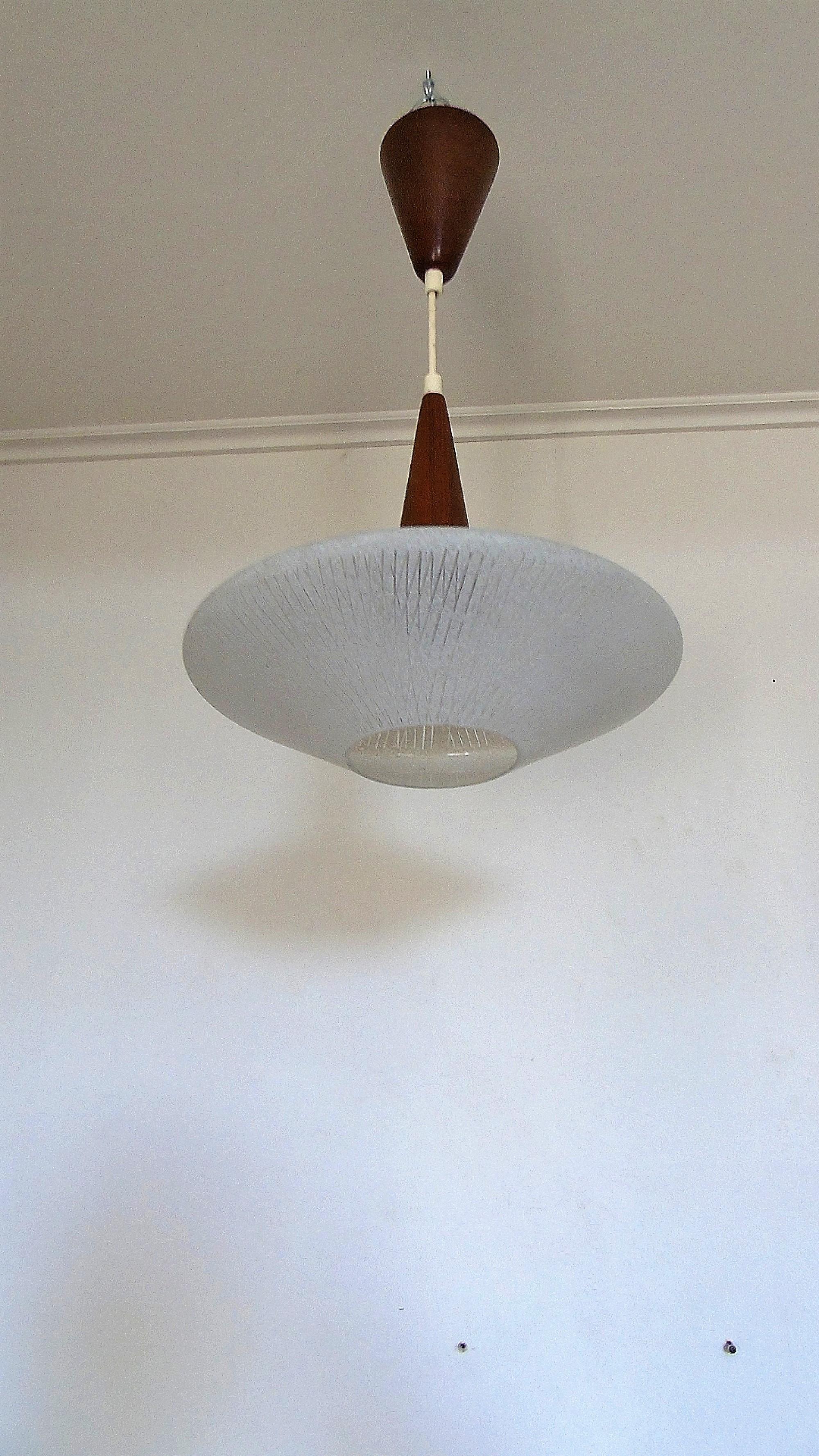 Beautiful Scandinavian teak and glass pendant light.

The glass is designed in a way to emit a diffuse light.

Good condition, no chips to the glass.

Tested and ready for use with a regular E26/E27 light bulb.

Denmark,