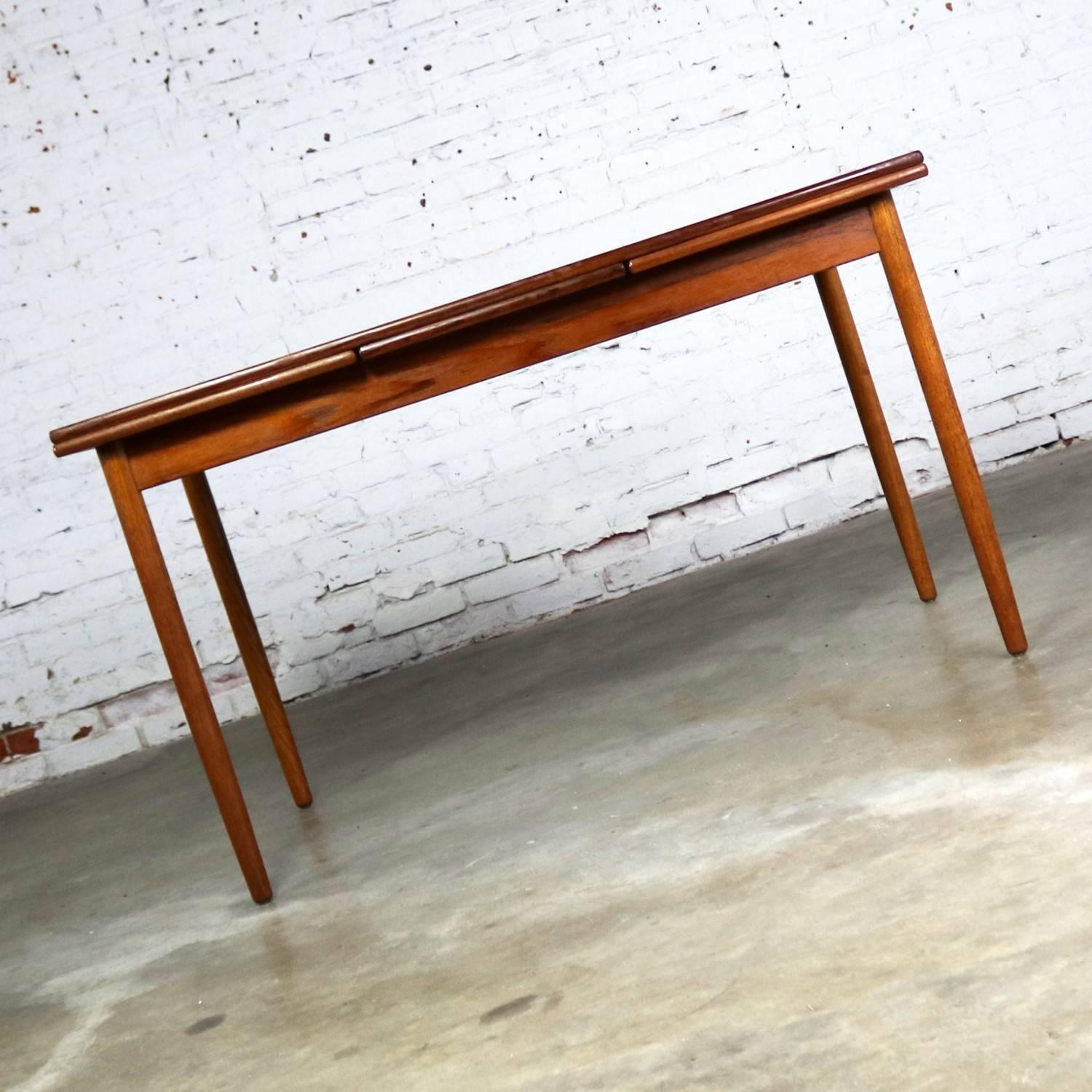 Handsome midcentury Scandinavian modern rectangular extending dining table of gorgeous and warm teak with draw leaf extensions. It is marked made in Denmark and is in overall fabulous condition. It is sturdy, and its finish has been restored to its