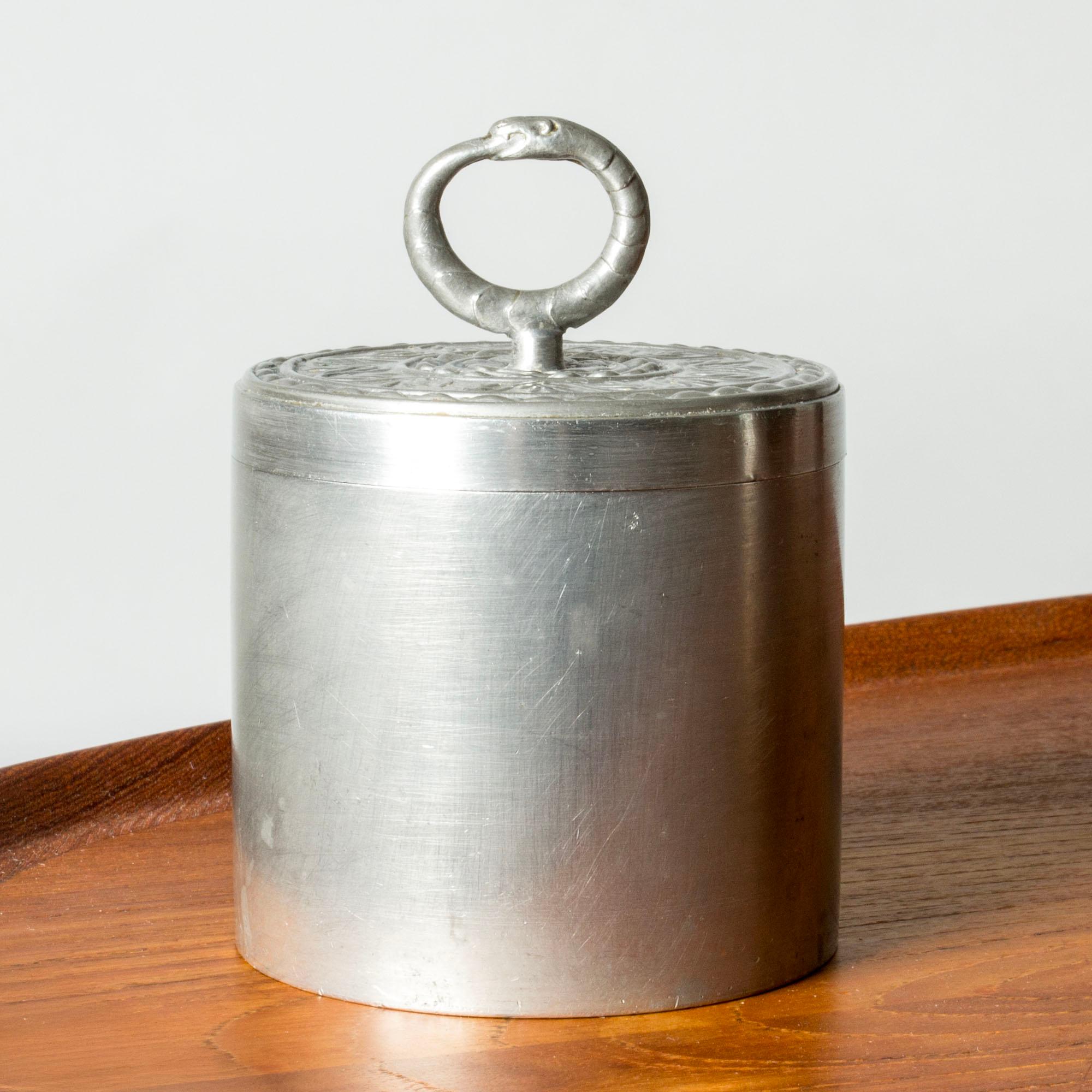 Eleganter Zinnkrug von Svenskt Tenn, mit einem kunstvoll mit Blättern und Ranken verzierten Deckel. Reifenknopf in Form einer Schlange, die sich in den Schwanz beißt.