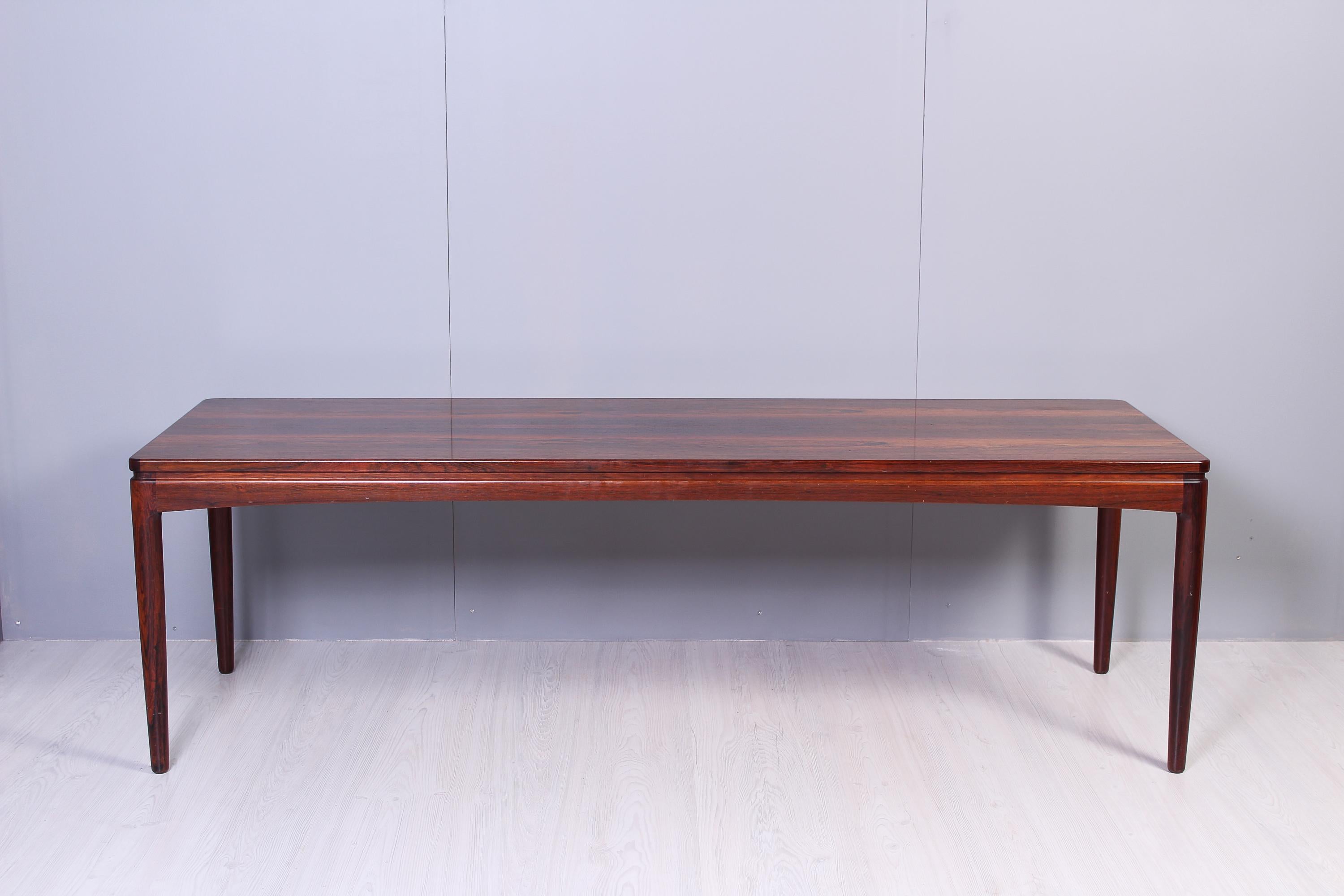 A long rosewood coffee table with in excellent vintage condition. The table has a pull out top on one of the sides that elegantly fits into the side without any handle. The table has sleek lines and nice details.