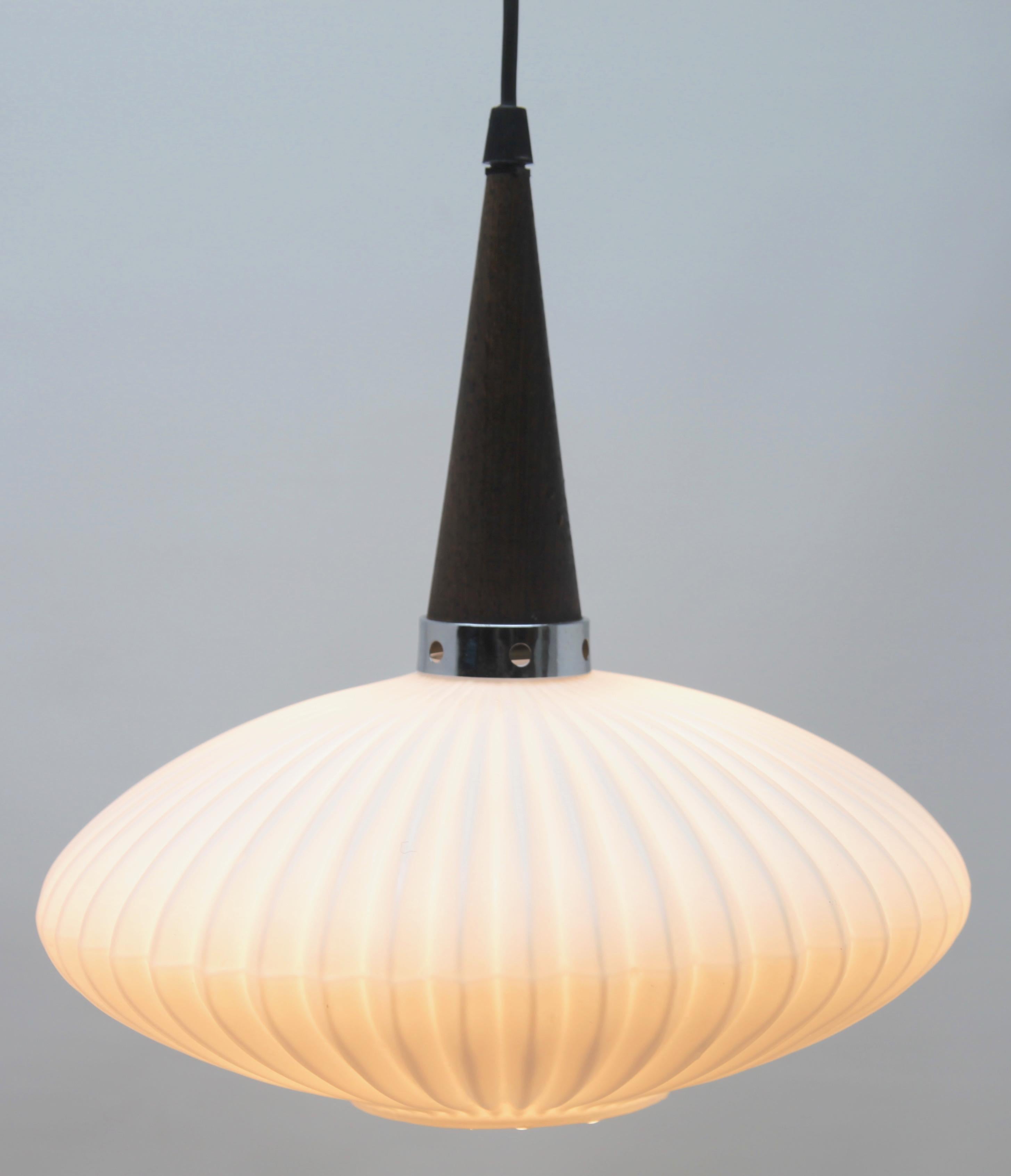 Hanging pendant light from the late 1960s on an adjustable cable, designed in the Scandinavian style with Wenge wood and an opaline shade. Its Classic modernist form and simplicity in design, make it an iconic example of midcentury home