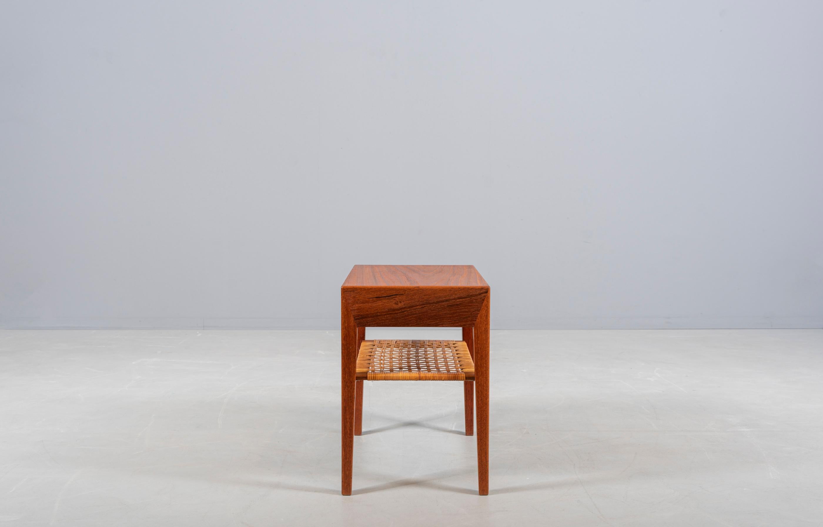 Petite table d'appoint ou de nuit en teck. Design de Severin Hansen Jr, fabriqué par Haslev Furniture au Danemark dans les années 1950. Un tiroir, une tablette de canne. De beaux détails.

