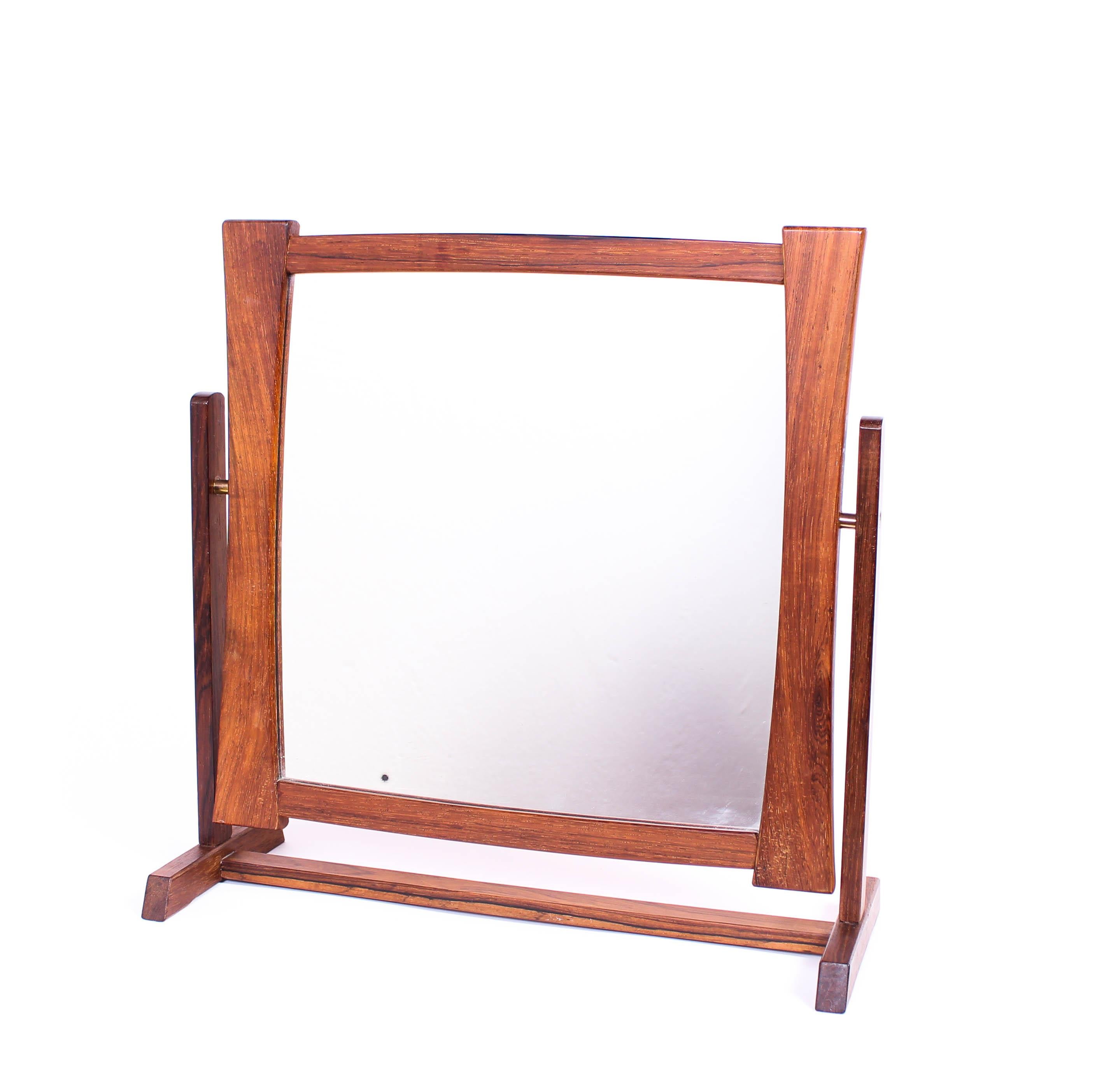 A midcentury table mirror by unknown Scandinavian designer. The mirror is made out of rosewood with brass fittings. Very good vintage condition, one small dark spot on mirror.