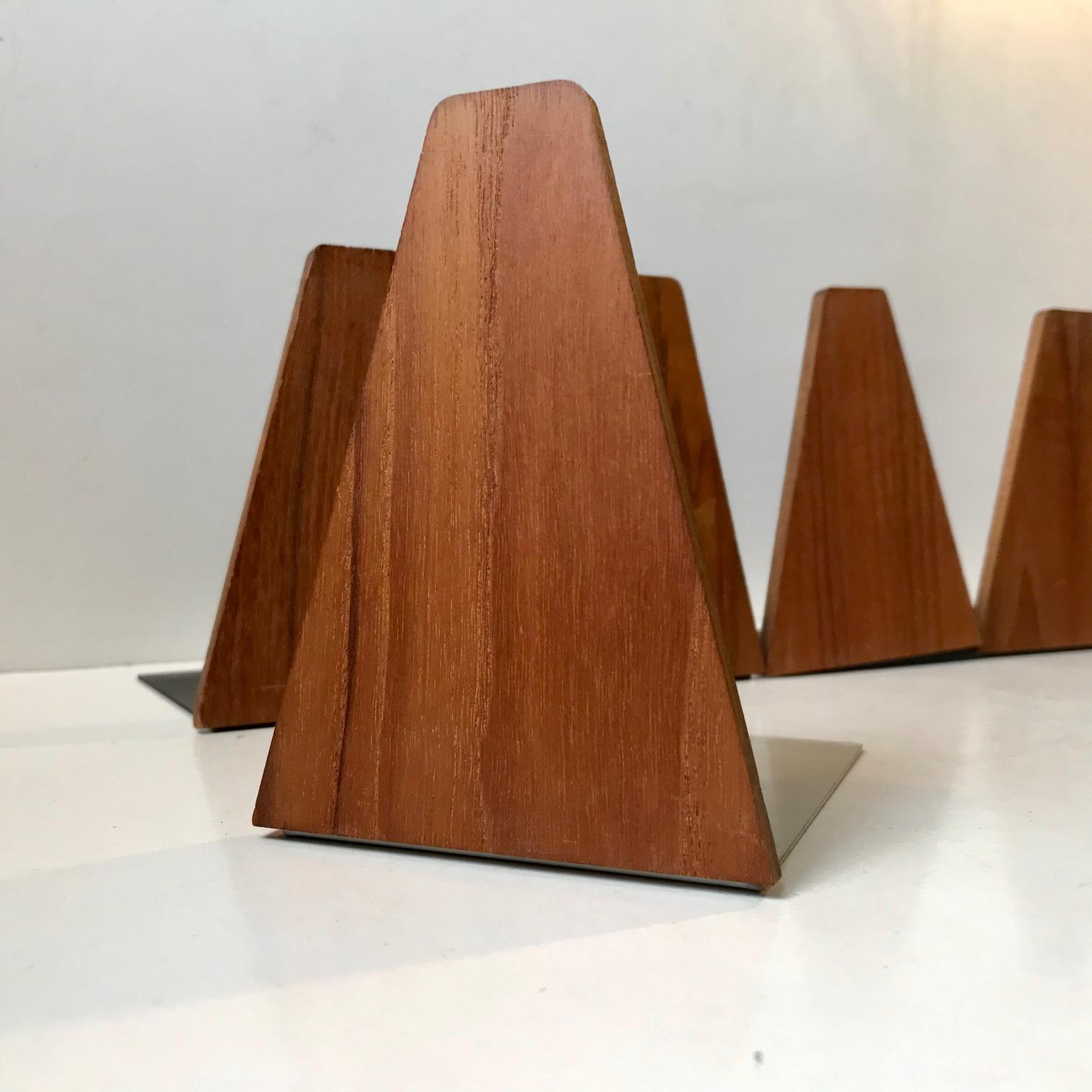 A set of 9 bookends in untreated teak with steel rest's manufactured by ESA in Denmark during the 1960s or 70s. The design is similar to bookends attributed to Kai Kristiansen. Measurements: Height: 12 cm, depth: 11 cm.
