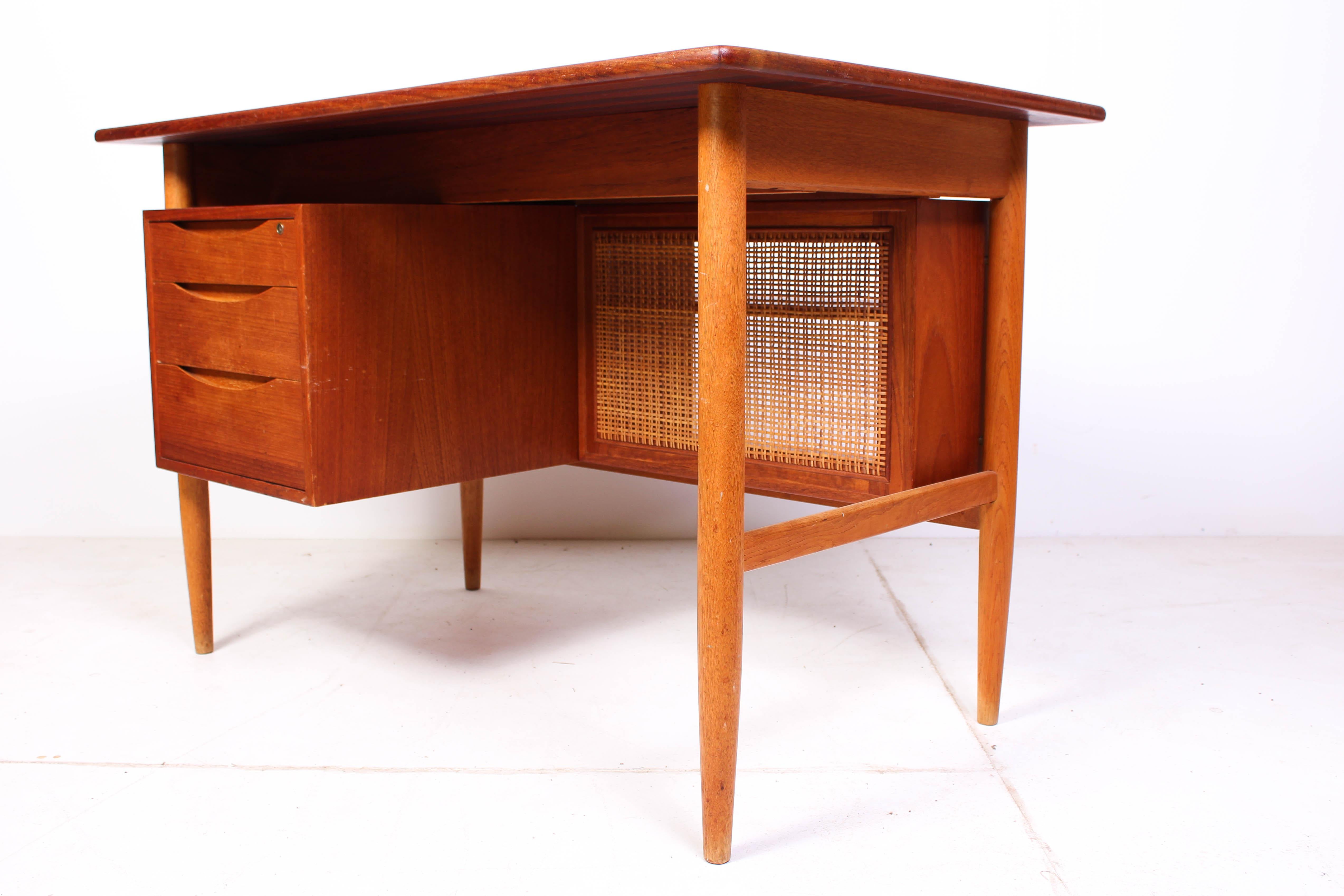 A midcentury Scandinavian Modern teak desk by unknown Scandinavian designer. The desk is made out of teak with oak legs and a cane shelf. It is a very decorative desk. It is in good vintage condition with signs of usage consistent with age. There