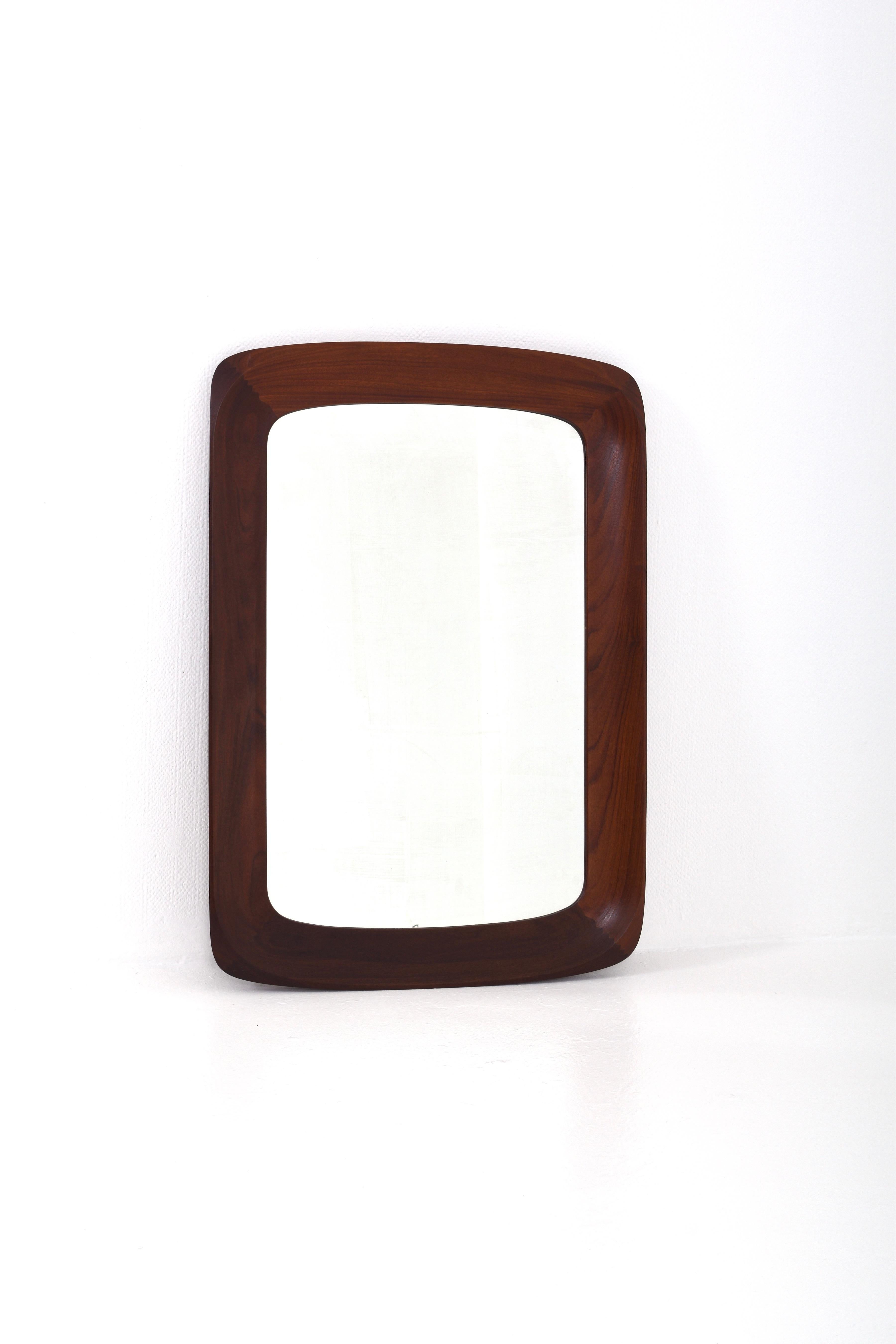 This mirror is a really fine piece of craftsmanship, with wonderful details and shapes. The frame is made of solid teak, the color is dark brown.

It is in fine vintage condition, there is age-related wear on the glass.
The mirror is labeled on the