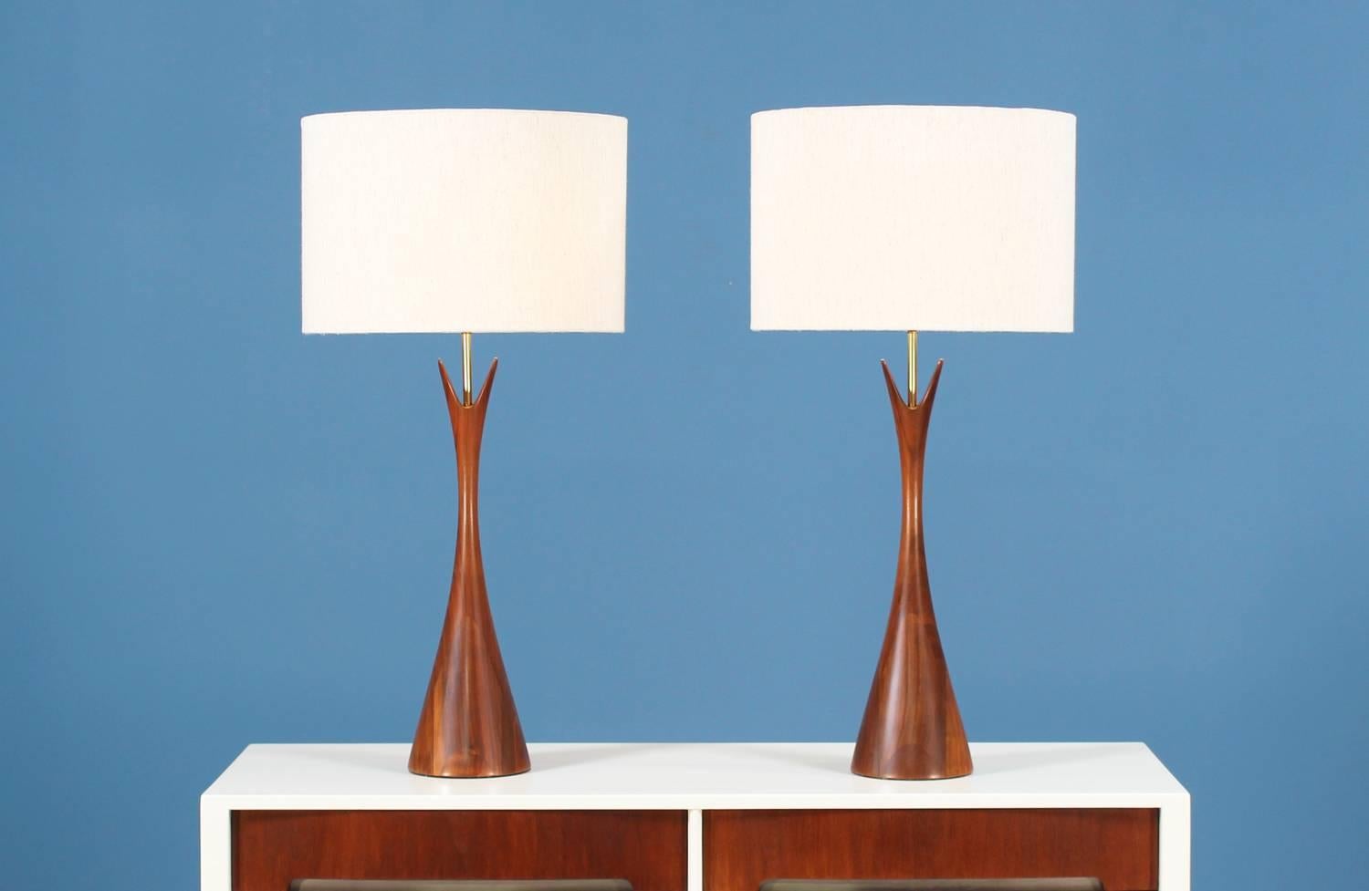 Mid-Century Modern walnut table lamps manufactured by Modernera Lamp Co. in the United States in the 1960’s. The sculpted walnut bodies resemble the shape of an hourglass with two prongs on top creating a mixture of artistic shape and is