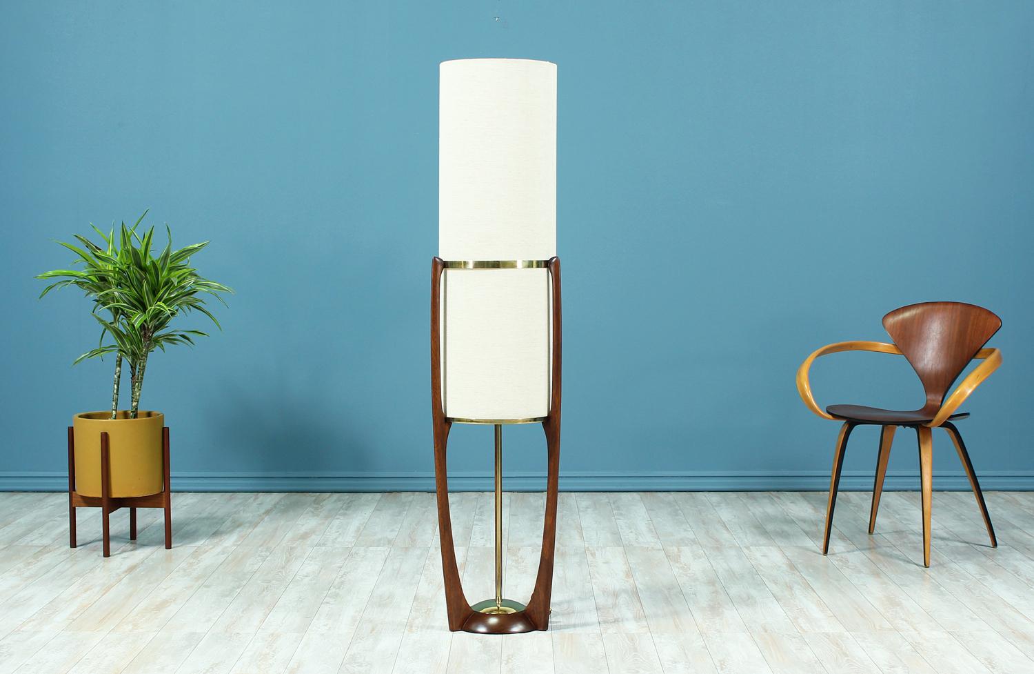 Dazzling floor lamp designed and manufactured by Modeline Lamp Co. in the United States circa 1960’s. This sculptural lamp features a walnut wood frame accentuated by brass hardware that supports the new cylindrical linen shade. This lamp has been