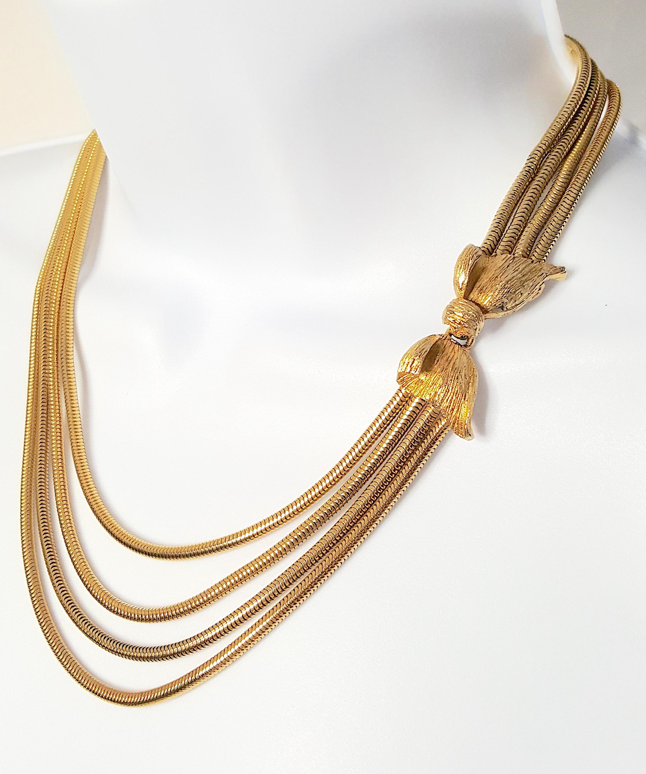 This mid-century shiny yellow-gold-plated snake-chain multi-strand necklace features a sculptural finely-textured gilt-metal bow that is positioned to rest on the upper left chest to function as a hook-and-eye clasp. Among the four graduated chains
