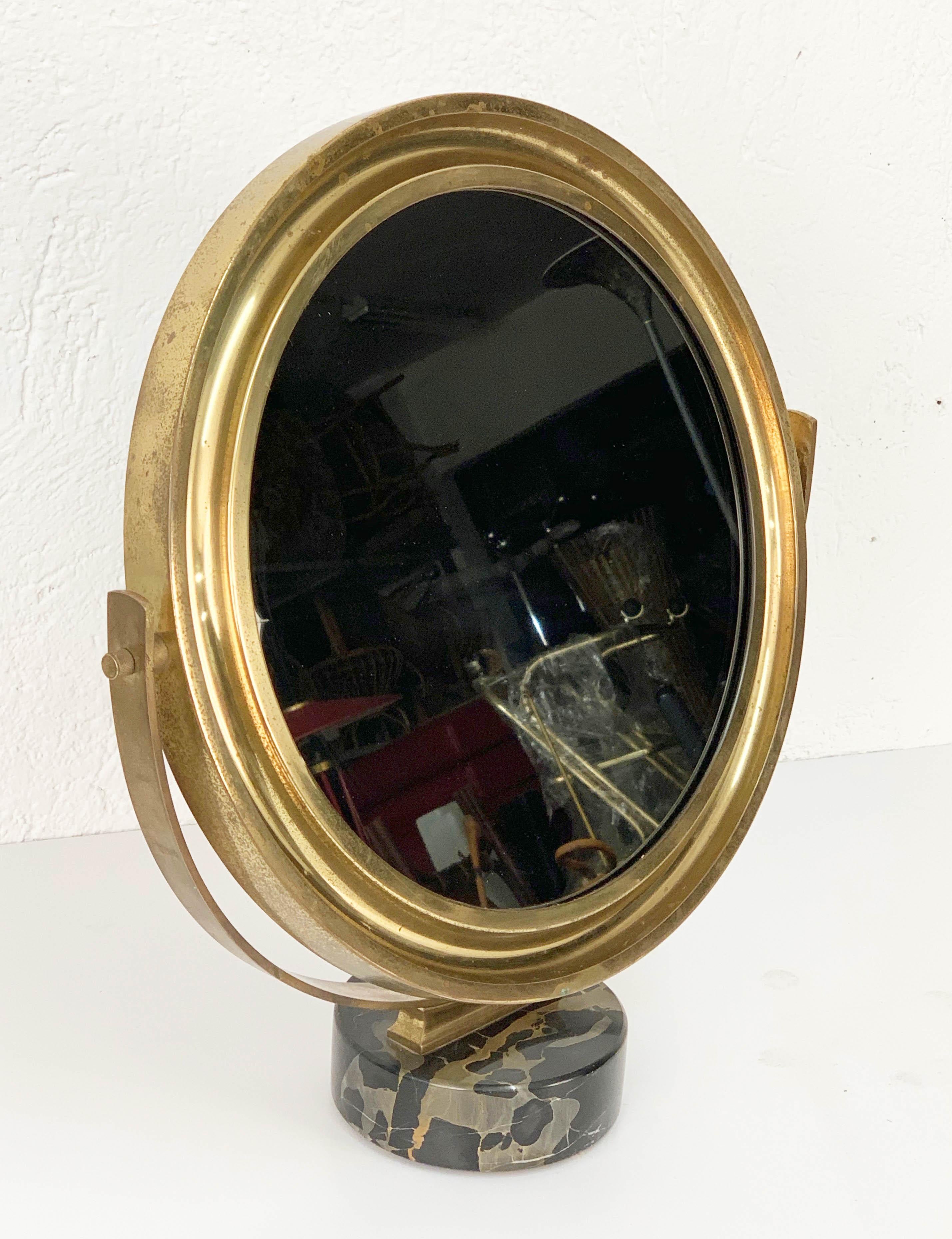 Midcentury brass table mirror with a black marble base. This fantastic item was designed by Sergio Mazza for Artemide, and it was made in Italy during the 1960s.

This surprising piece is composed of a rotating mirror in brass and a marble base.