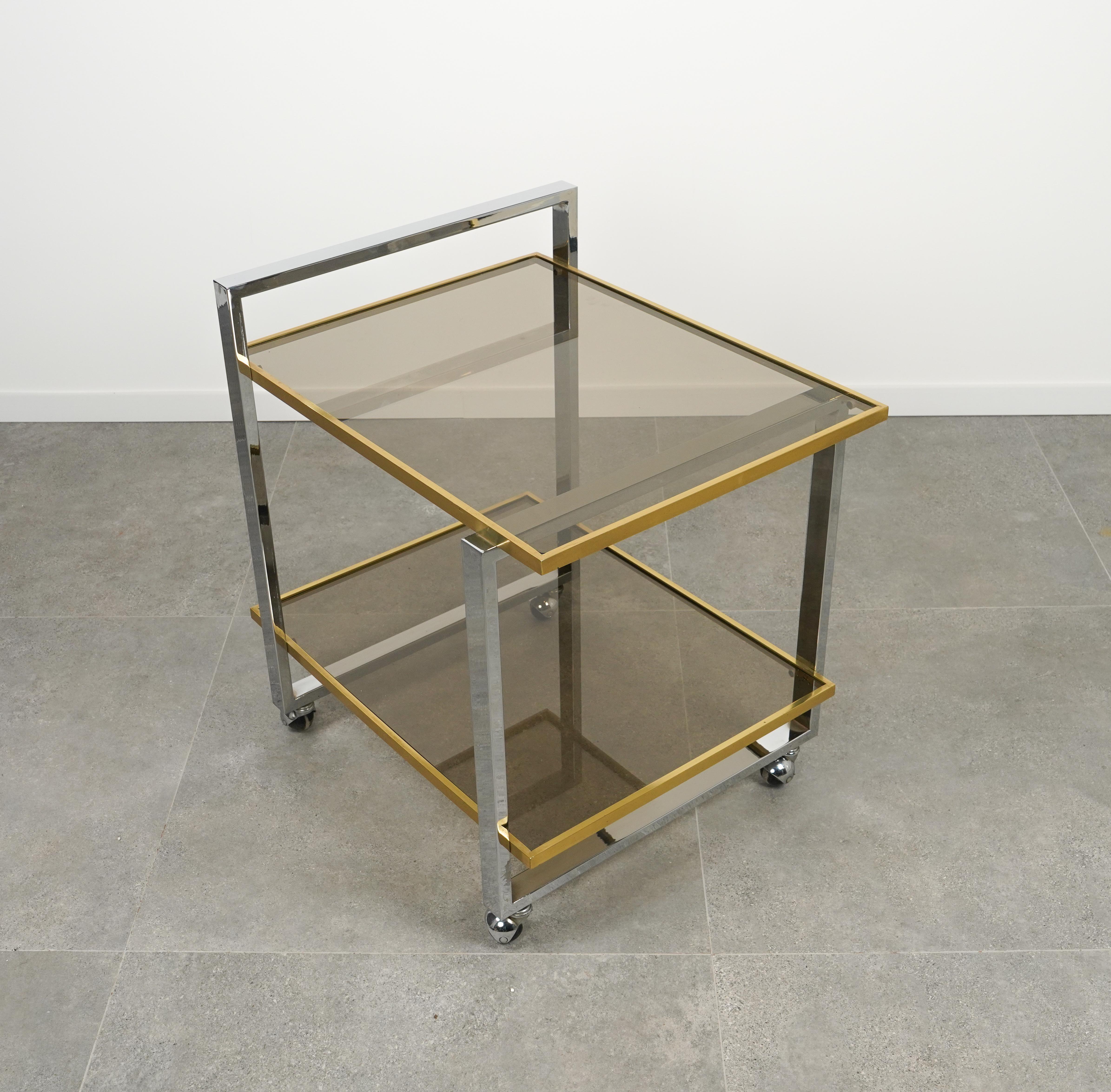 Midcentury beautiful serving bar cart / trolley in chrome, brass and two smoked glass shelve smoked glass attributed to Romeo Rega.

Made in Italy in the 1970s.