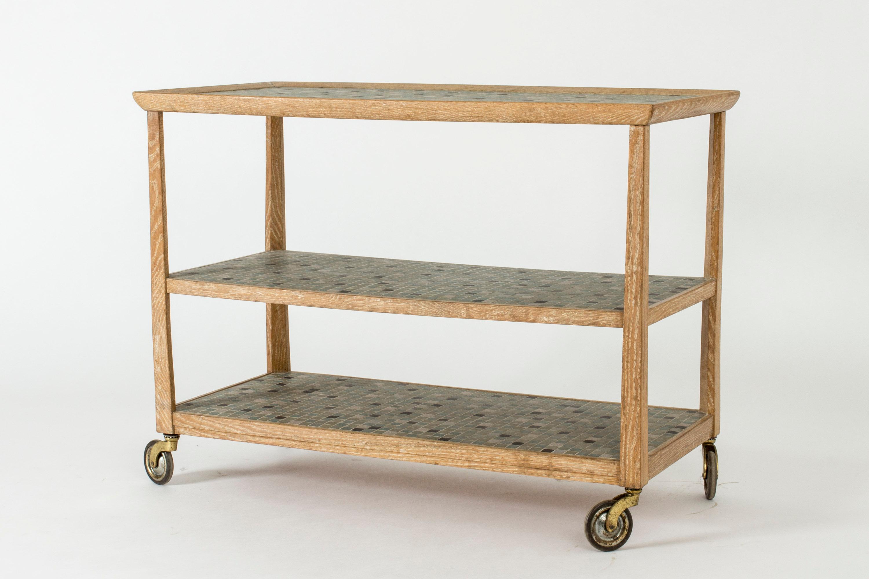 Beautiful bar trolley by Otto Schulz made from white-washed oak that brings out the wood grain in a great way. Shelves decorated with ceramic tiles in subdued greens and black. Wheels in great condition.