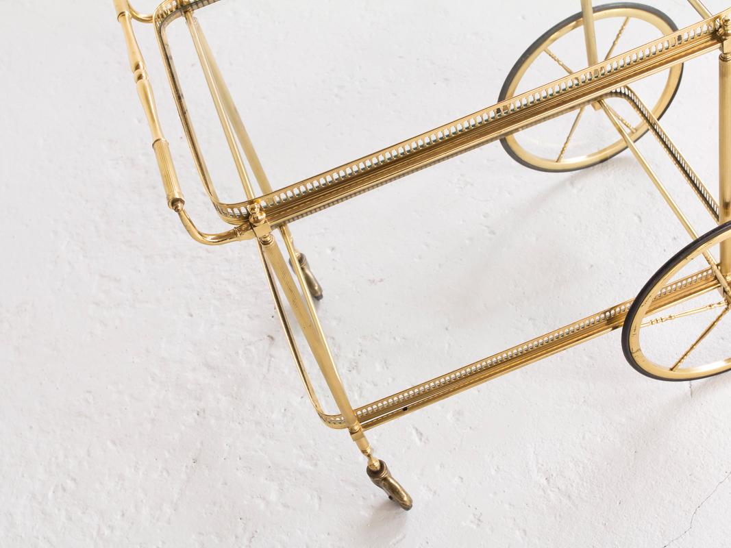 This midcentury serving trolley was manufactured by Maison Baguès in Paris, France in the 1950s. It is ideal as bar cart. It has 2 levels and the serving plates can be taken out. It is made of brass and glass. All parts are original and in very good