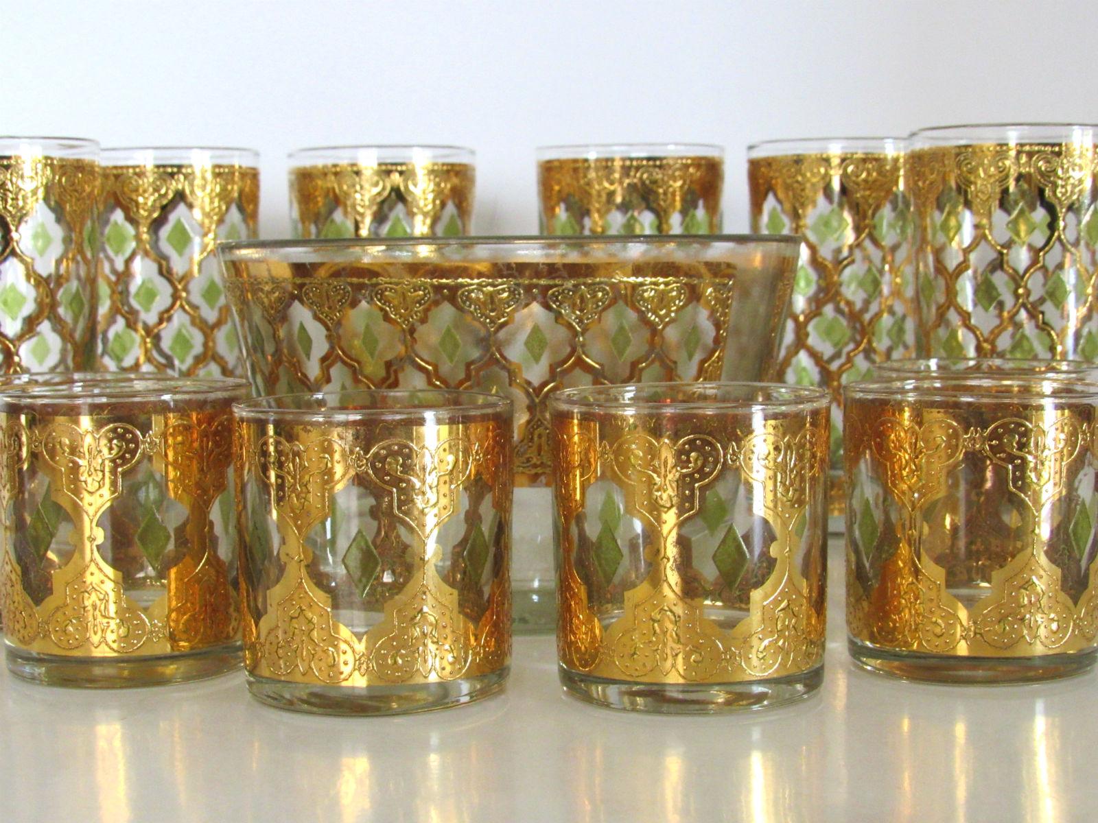 Exquisite set of six highball glasses, 6 shot gasses and ice bucket by Culver, circa 1962. This set has a highly ornate 22 Karat gold textured filigree design with raised green diamond accents. Highball glasses in excellent condition, some very