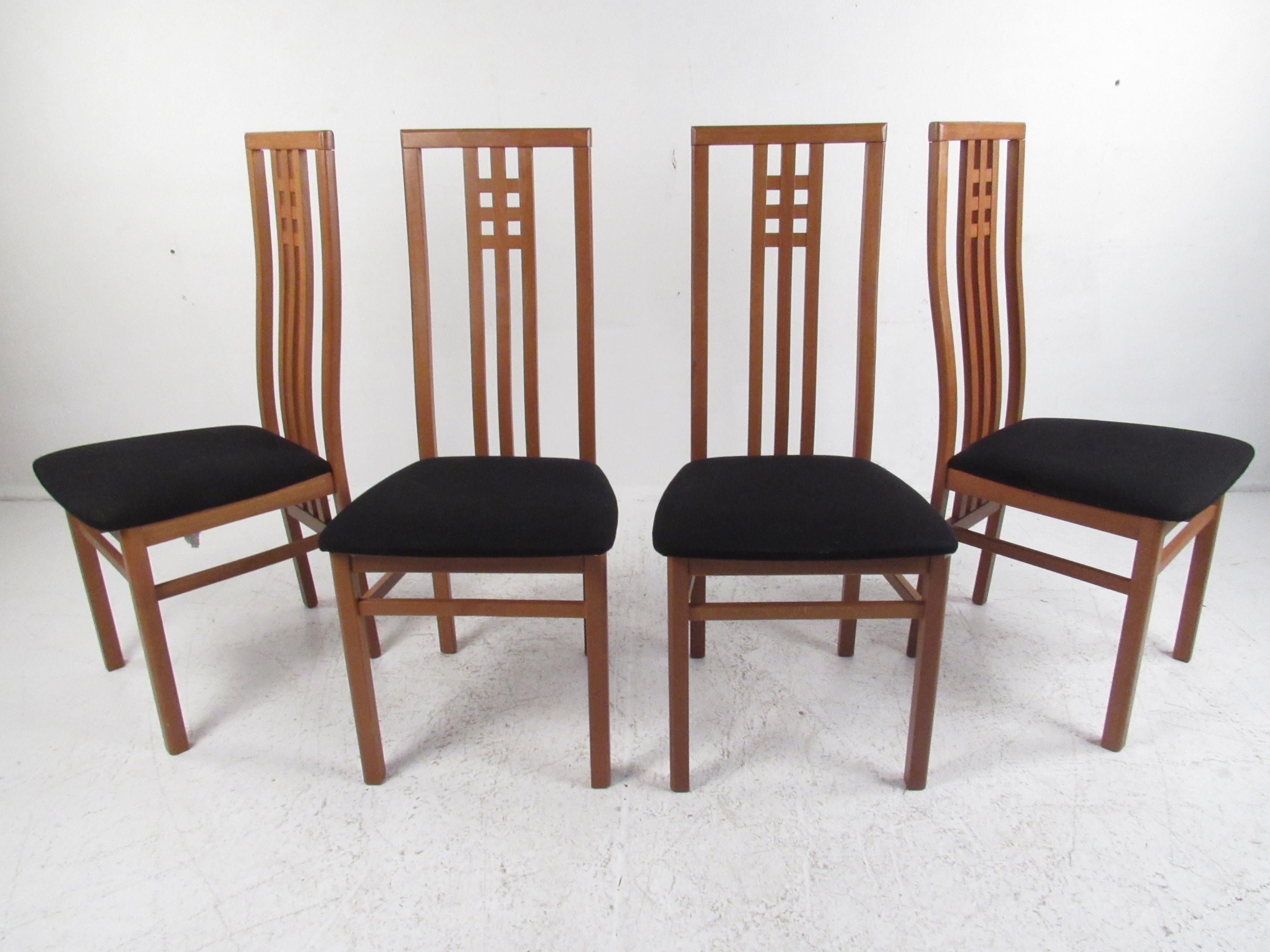 A stunning set of eight vintage modern dining chairs that boast high curved back rests with a unique square grid pattern near the headrest. An unusual design with plush dark fabric covering an overstuffed seat. The sculpted teak frame with