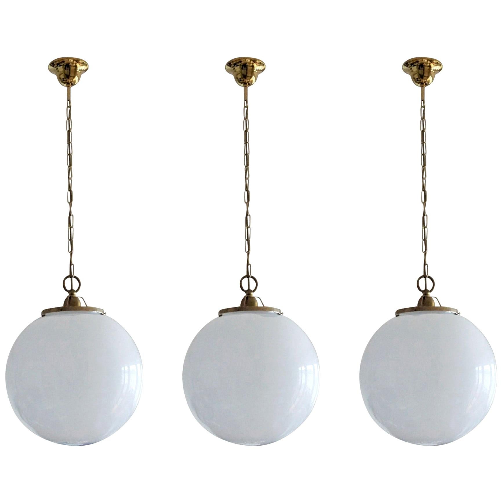 Set of thee large Italian ball hand blown opaline glass sphere pendants brass-mounted, with a single E-27 light socket for a large sized bulb, 1950s
Measures: Diameter 14
