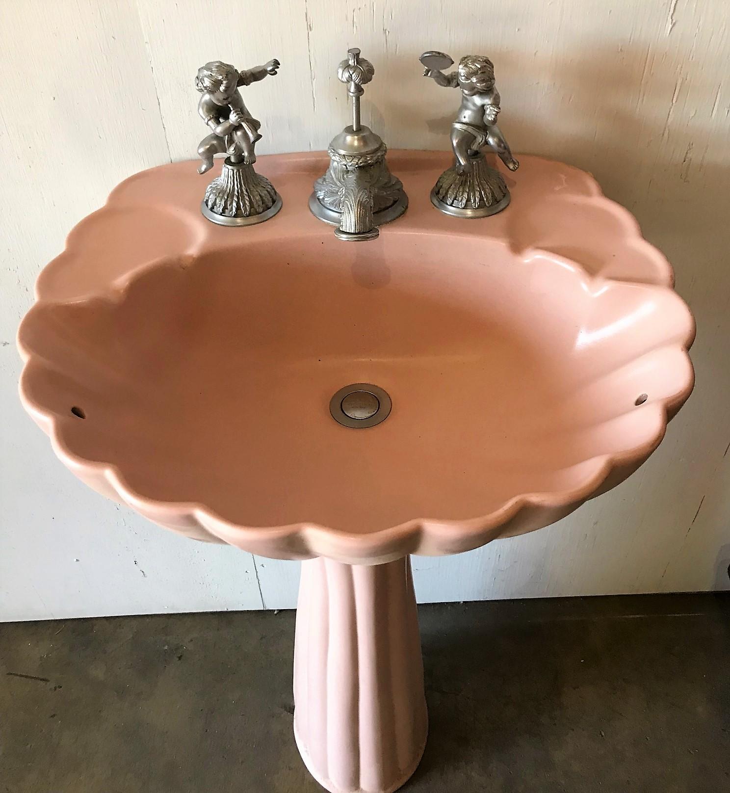 Highly sought-after Sherle Wagner pink porcelain pedestal sink with a scalloped shell-shaped basin and mounted with sculpted nickel-plated musical cherub handles. Acanthus leaf motif faucet and stopper. Stamped 