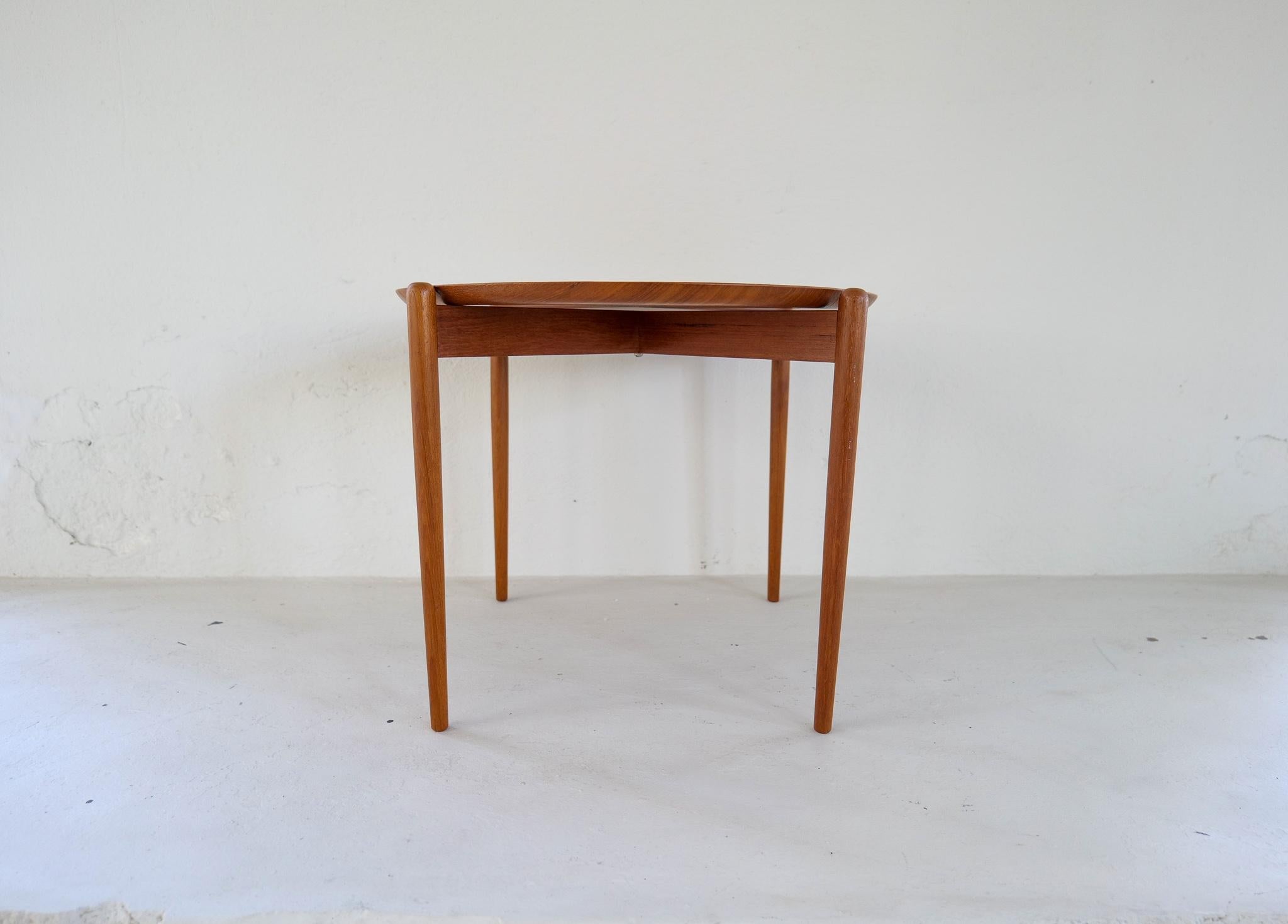 This neath teak tray table made in teak was made in Sweden during the early 1960s. 
The tray in nicely looking teak and removable. 

Good vintage condition with some wear and patina. 

Dimension: H 42 cm D 55 cm.
 