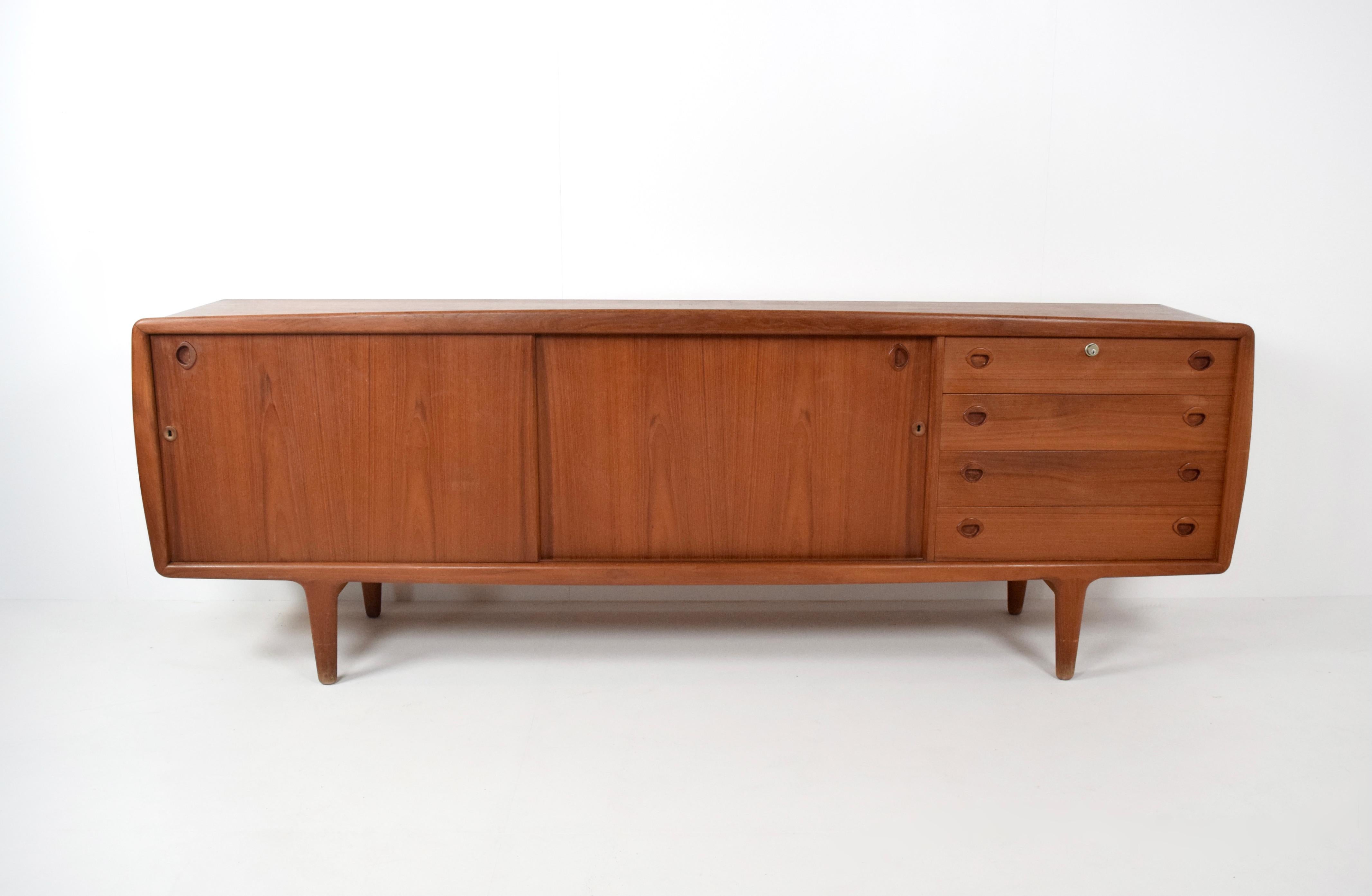 This sideboard by H.P.Hansen is a true example of Midcentury Danish Design. It has two sliding doors with shelves and four drawers on the right and key locks in both of the doors as well as the drawers. It is executed in teak and clearly marked on