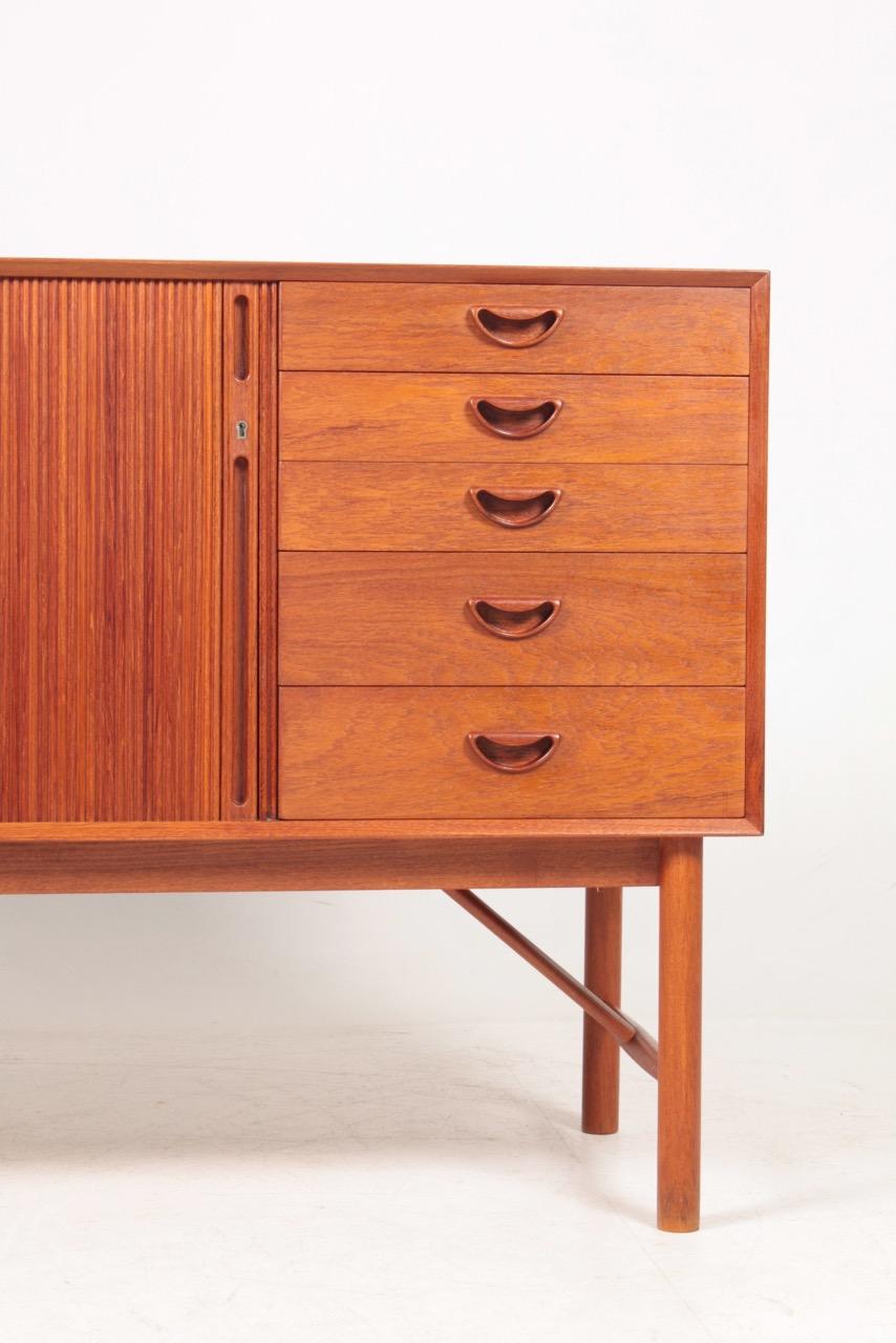 Sideboard in solid teak with a five drawers and tambour door. Finger- jointed case on round legs. Designed by Hvidt and Mølgaard for Søborg Møbler in 1958. Made in Denmark. Great original condition.