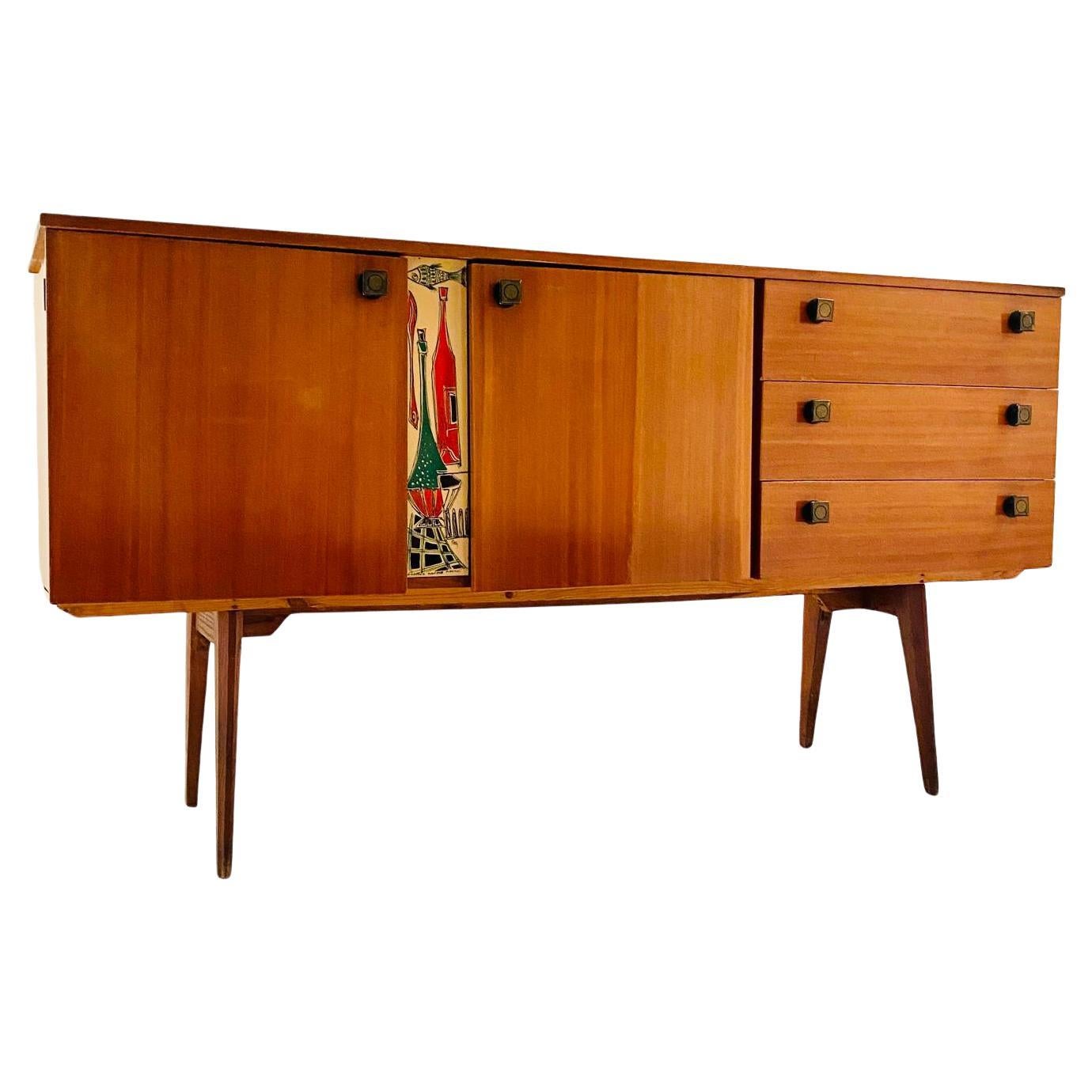 A 1950's vintage sideboard with lacquered finishing and beautiful ethnical drawing in pure Mid-Century Modern style. 

The sideboard is made by three drawers on one side and a two shutter opening case on the other one. The opening handles are made