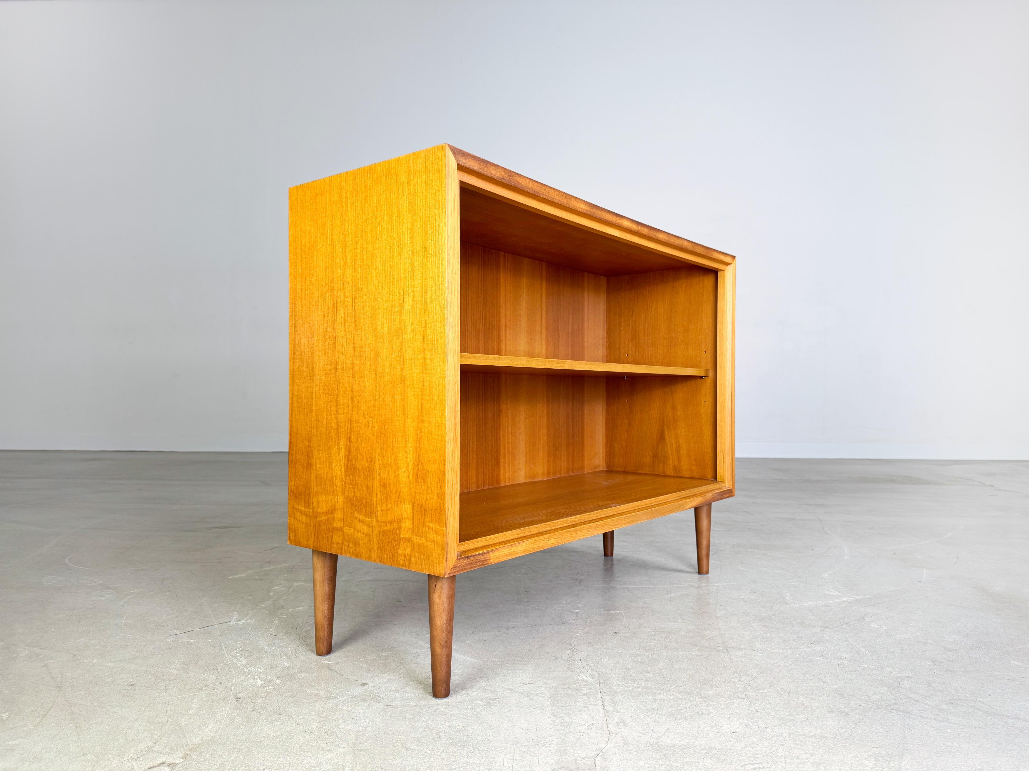 Wir bieten ein wunderschönes kleines WK Möbel Sideboard aus den 1960er Jahren zum Verkauf an. Das Sideboard verfügt über zwei Türen und wurde aus hochwertigem Nussbaumholz gefertigt. Die vier Füße sind aus gebeiztem Buchenholz und nachträglich